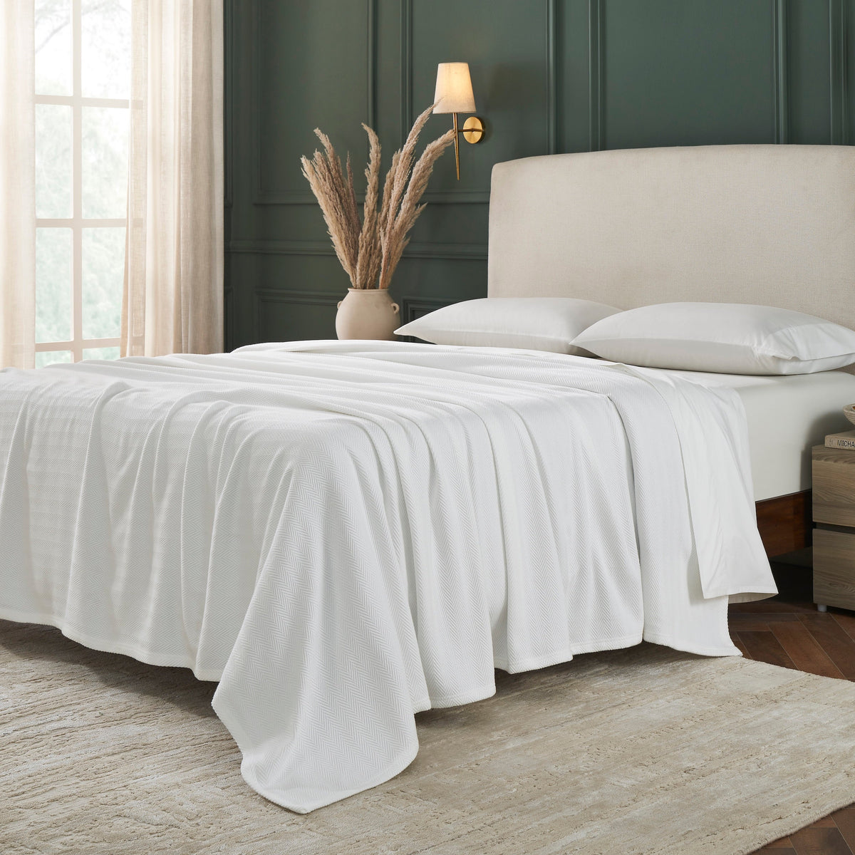 BL-865-9496_3|Soft white woven blanket elegantly draped over a sage green duvet, perfect for layering and enhancing a chic bedroom aesthetic.
