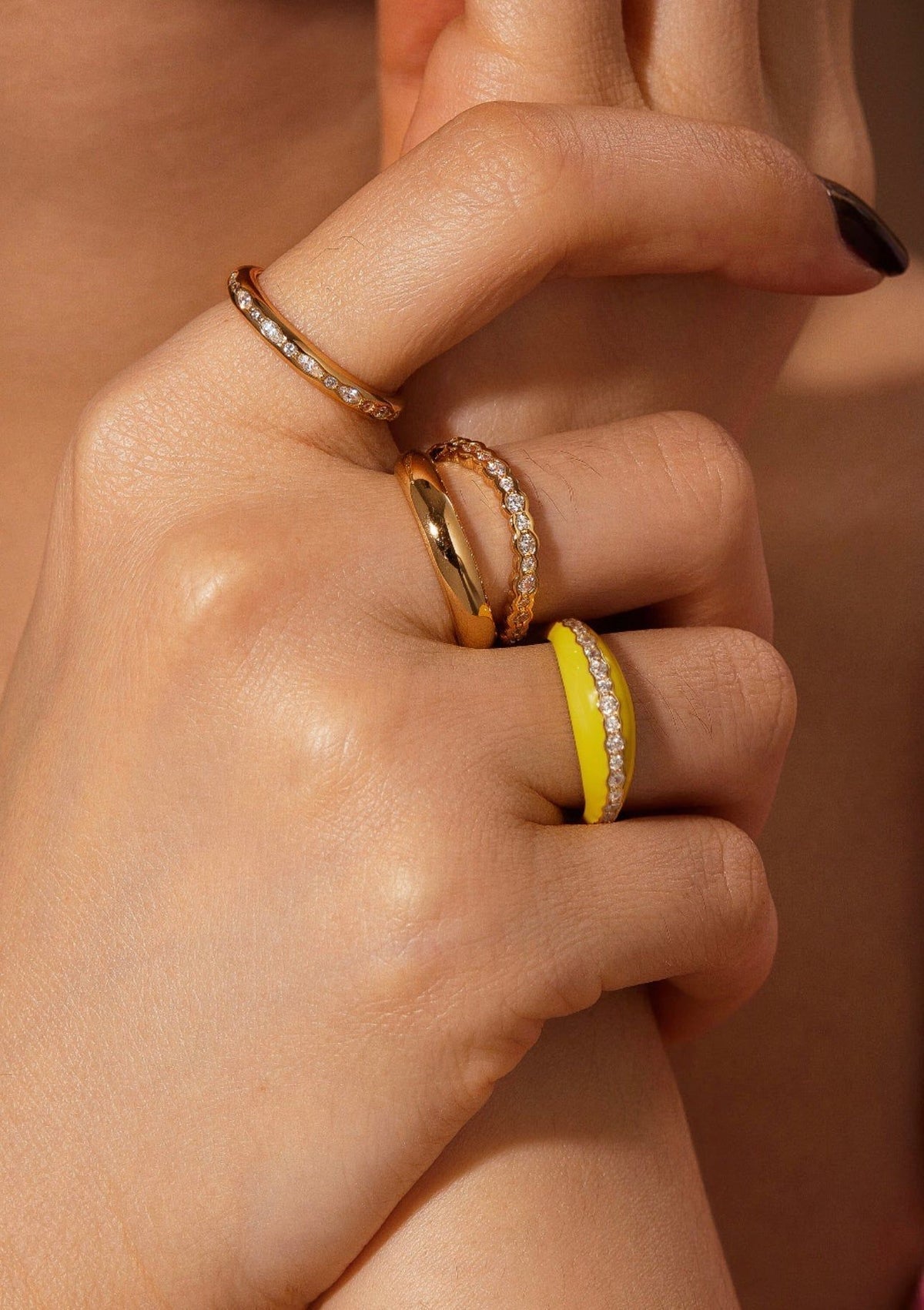 Hand with gold and yellow rings showcasing the Multi Shaped CZ Channel Ring effect