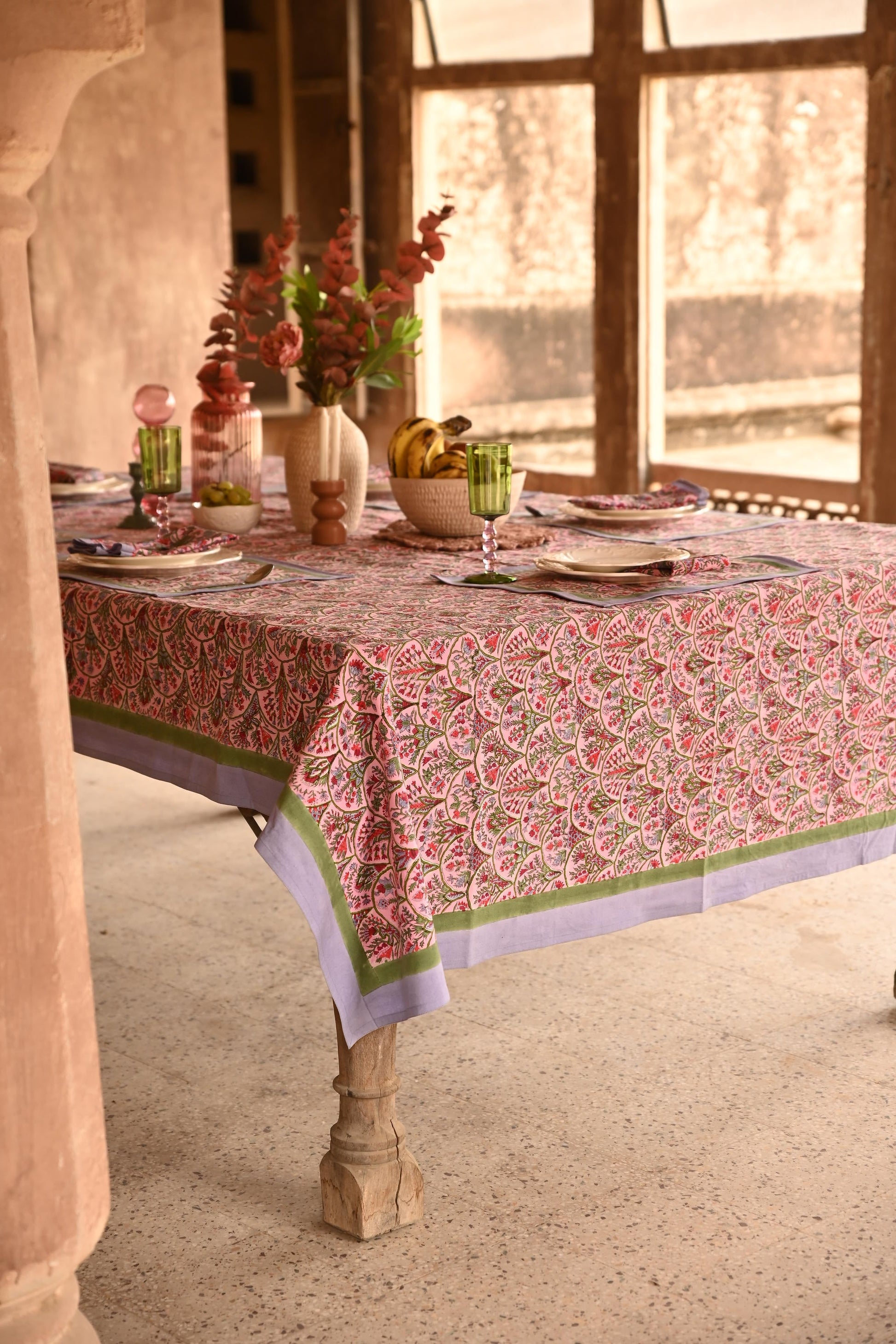 Pink arch blockprint tablecloth covering dining table in rustic interior setting