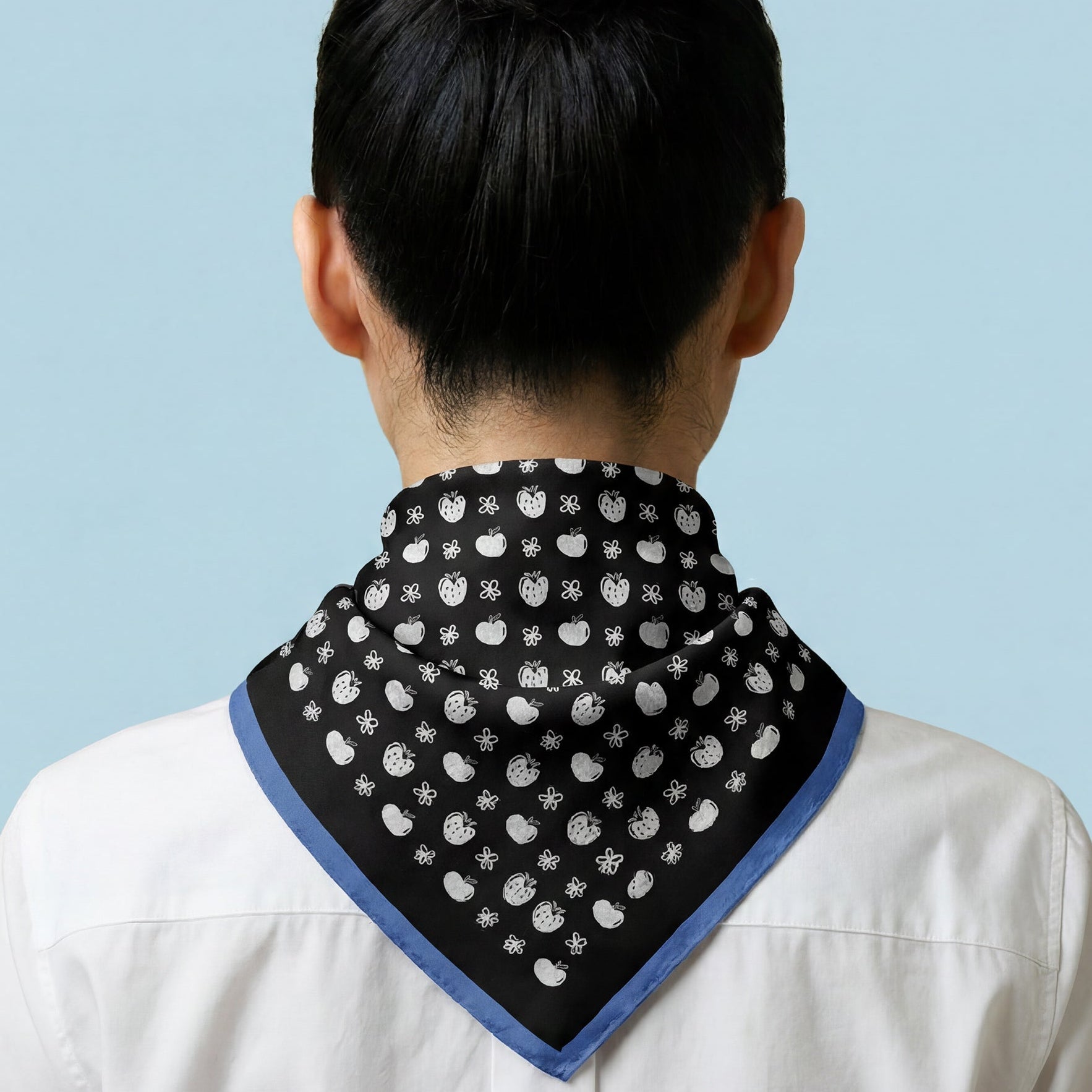 Person wearing a black and white patterned bandana on a light blue background