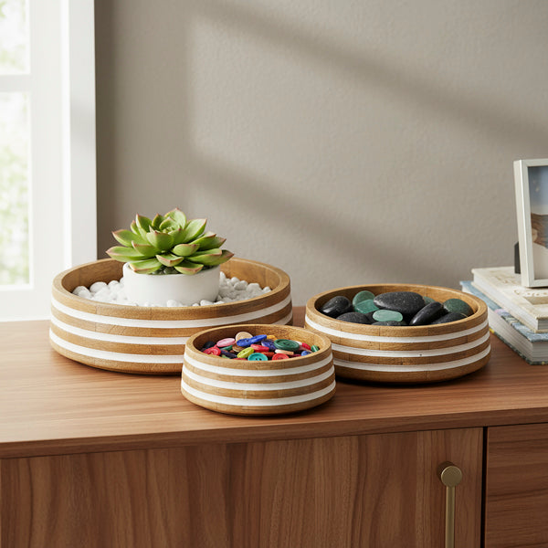 Handcrafted striped wooden bowls stacked on a modern kitchen counter near a window.