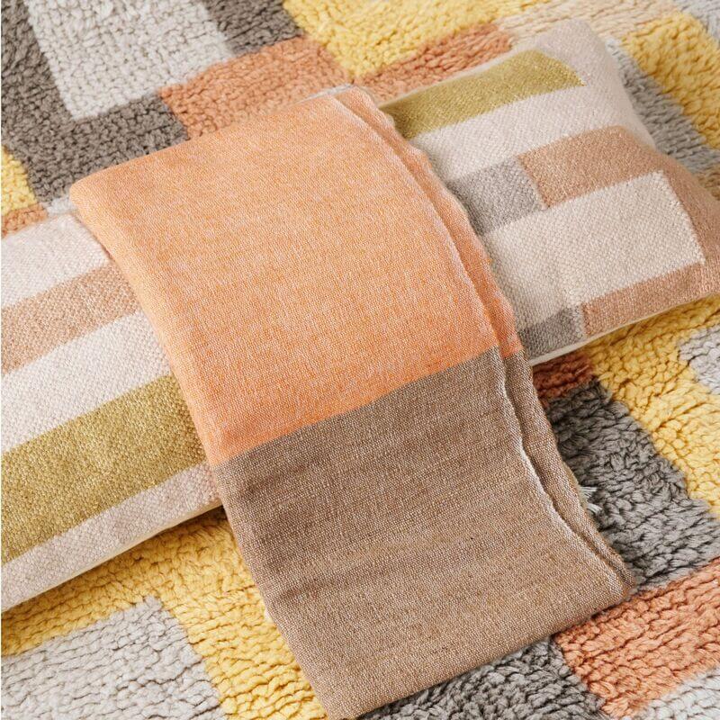 Shale Hand Woven Pastel Color Large Geometric Lumbar Pillow showcasing soft textures and pastel colors on a patterned rug.