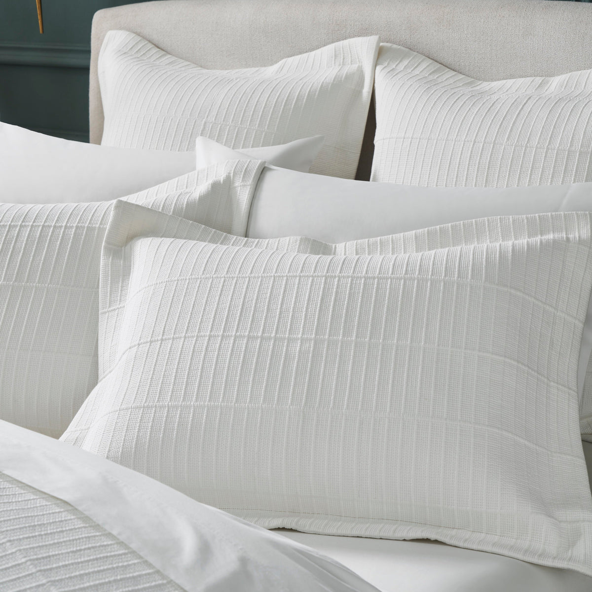 ES-268-2626_4|Crisp white textured coverlet set, including a folded coverlet and two matching pillow shams, neatly stacked and ready for use.
