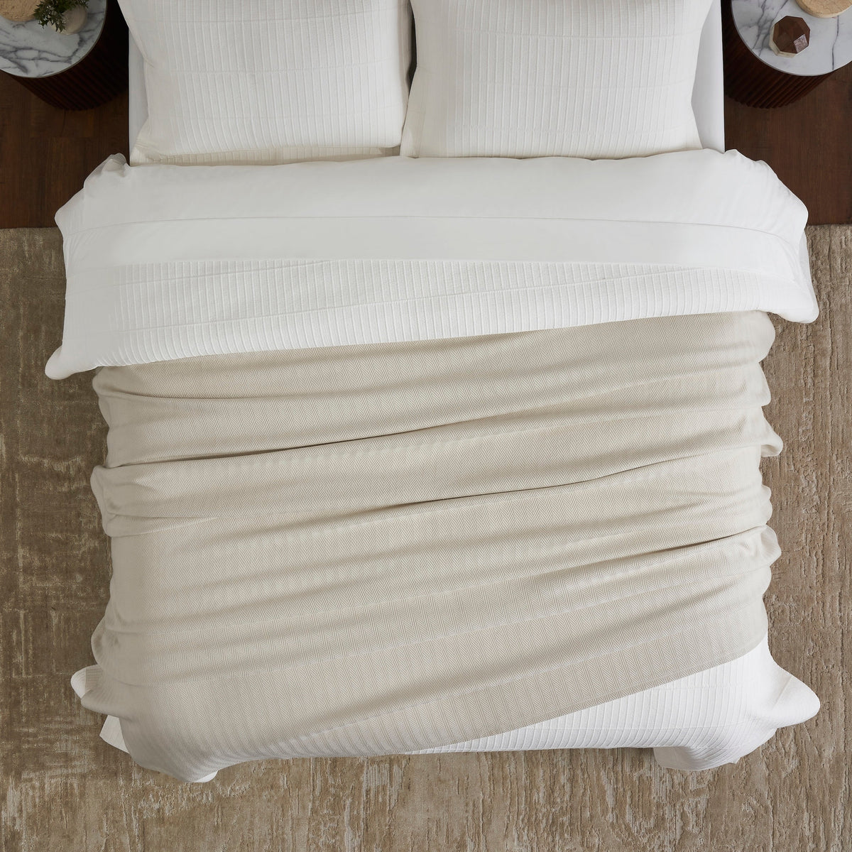 BL-866-9496_4|Overhead view of a cozy light beige herringbone textured blanket folded on a bed, showcasing its soft weave.