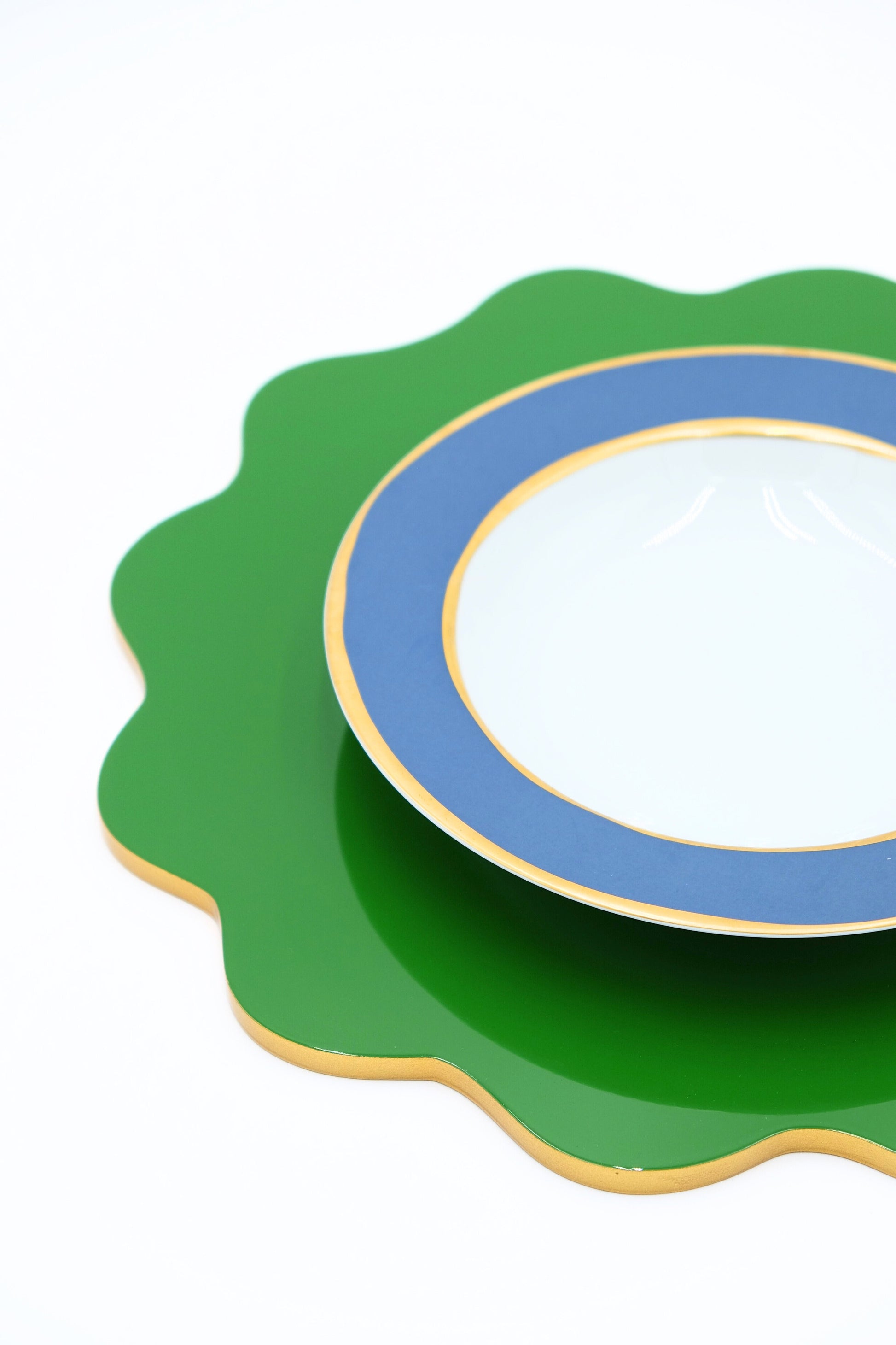 Close-up of garden green scalloped lacquerware placemat with blue-rimmed plate from Inner Child
