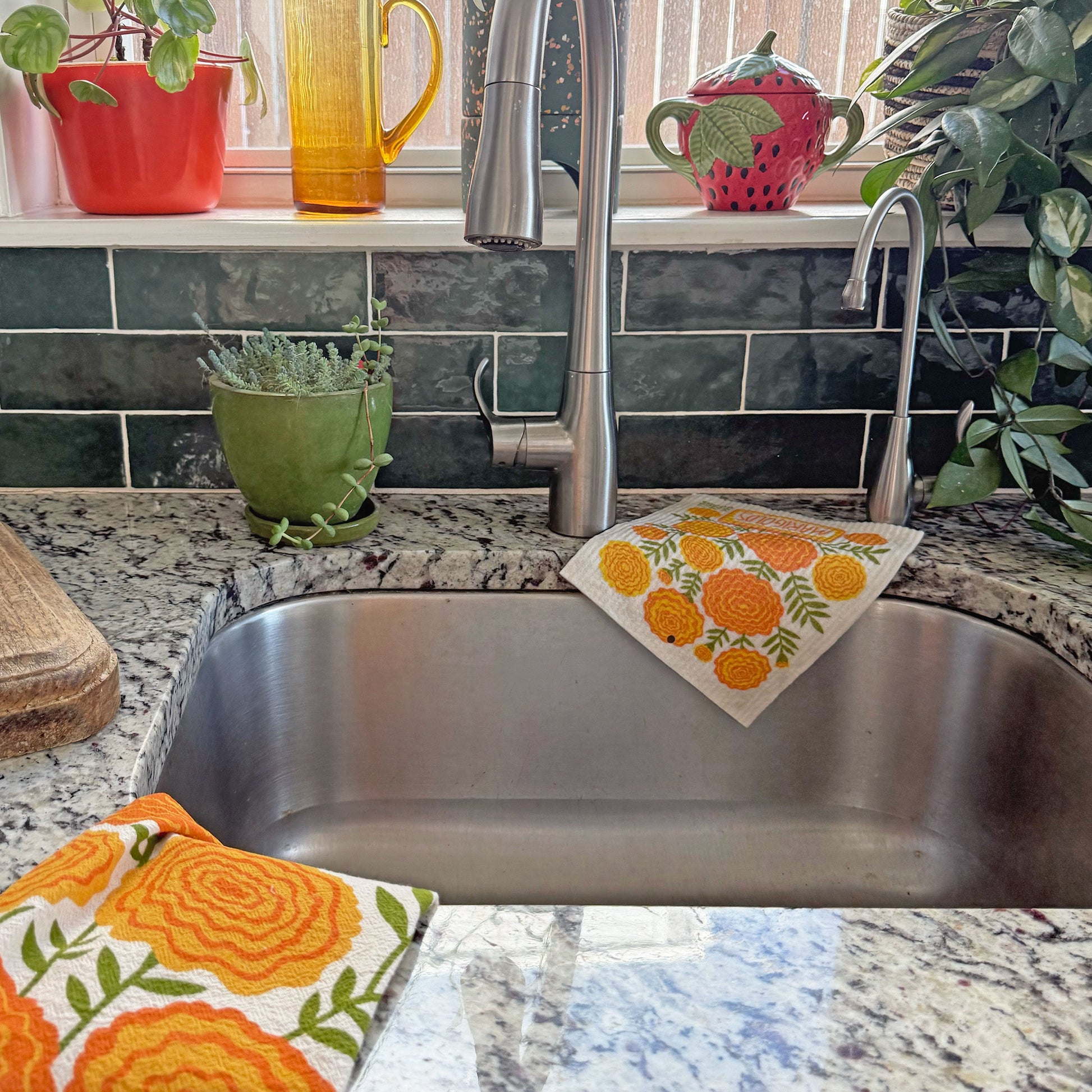 Marigolds dish towel and sponge cloth draped over a kitchen sink.