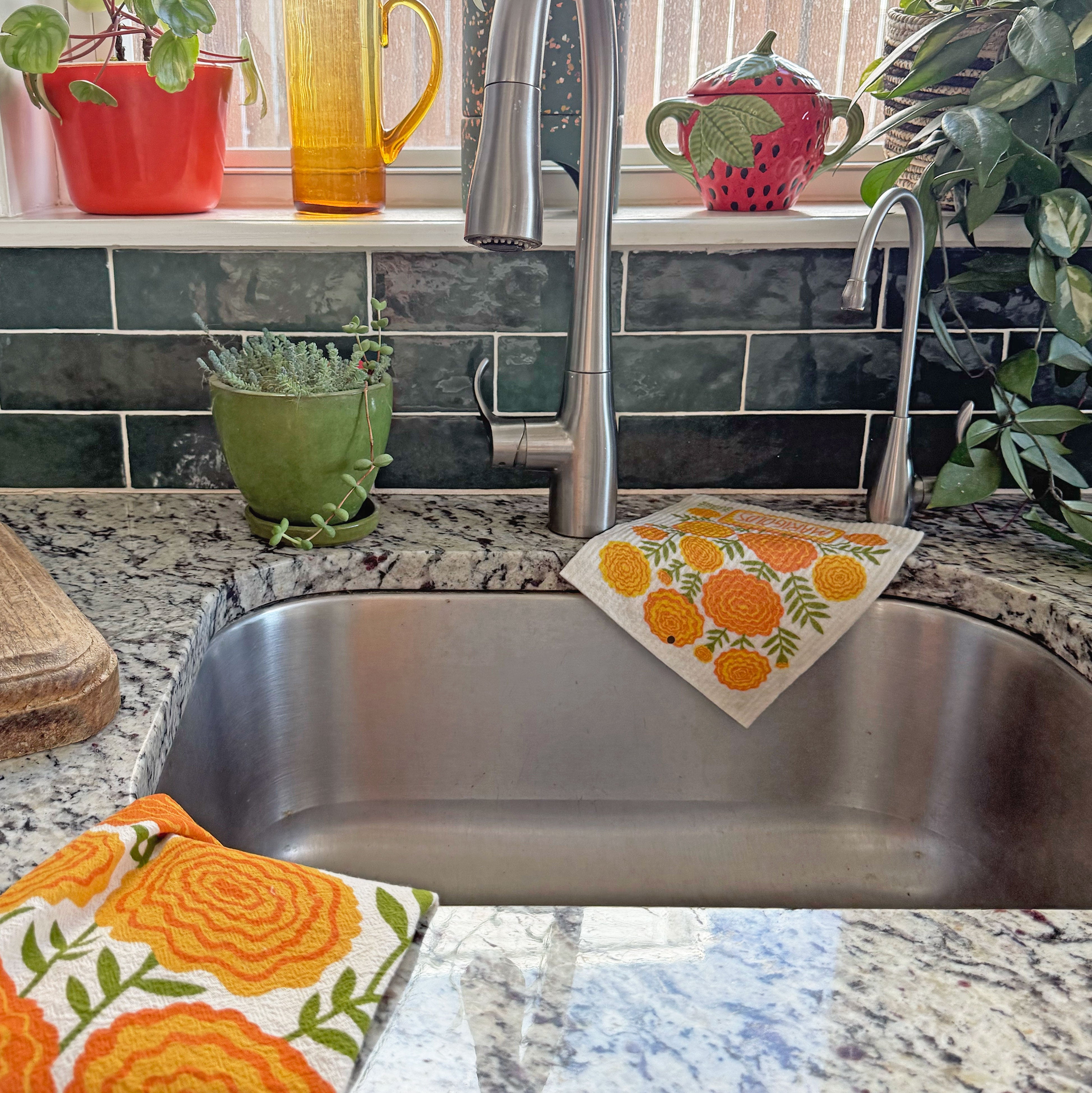 Marigolds dish towel and sponge cloth draped over a kitchen sink.