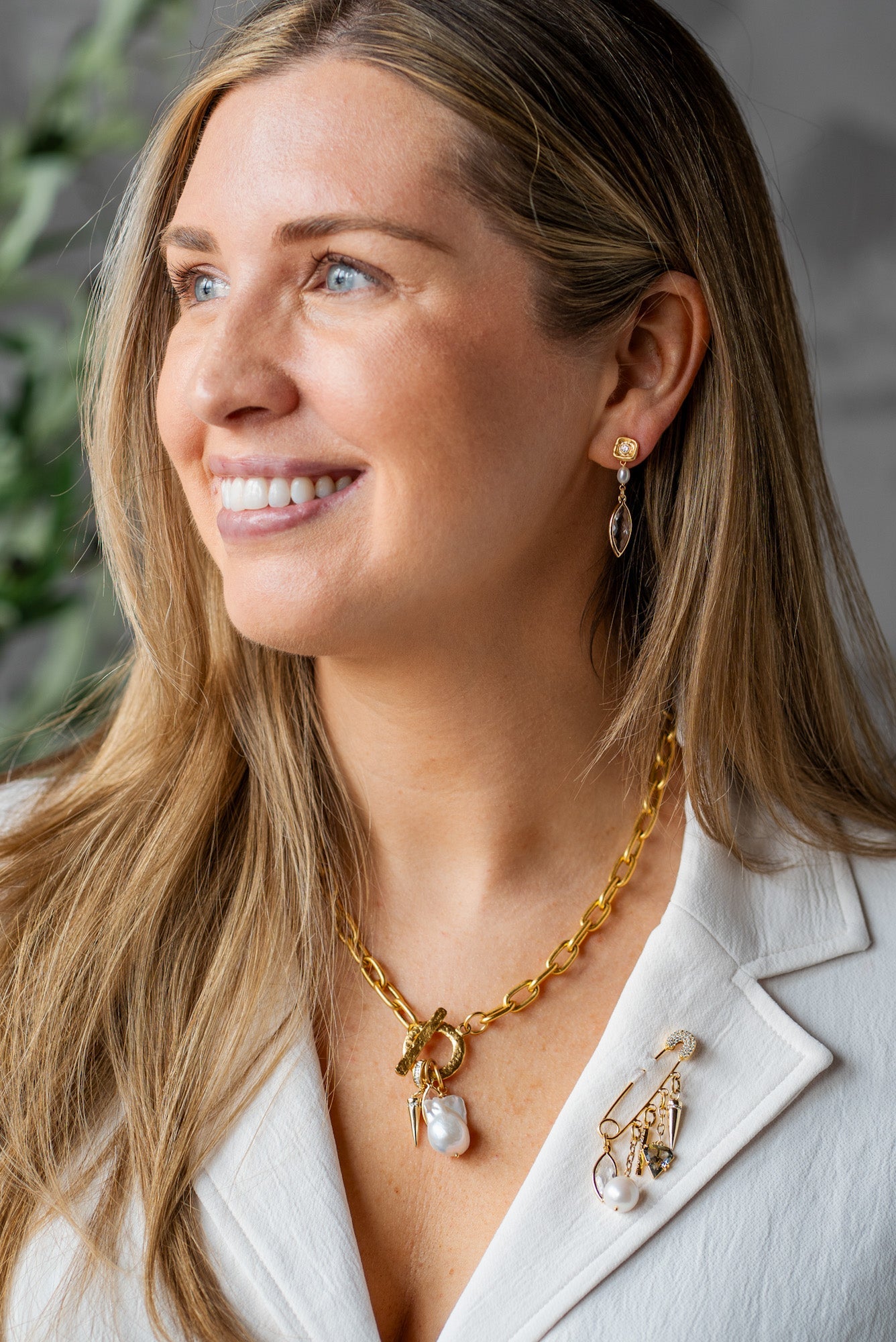 Gold brooch with dangling charms including marquis crystal, pearl, pave spike, smoky quartz triangle, and gold spike