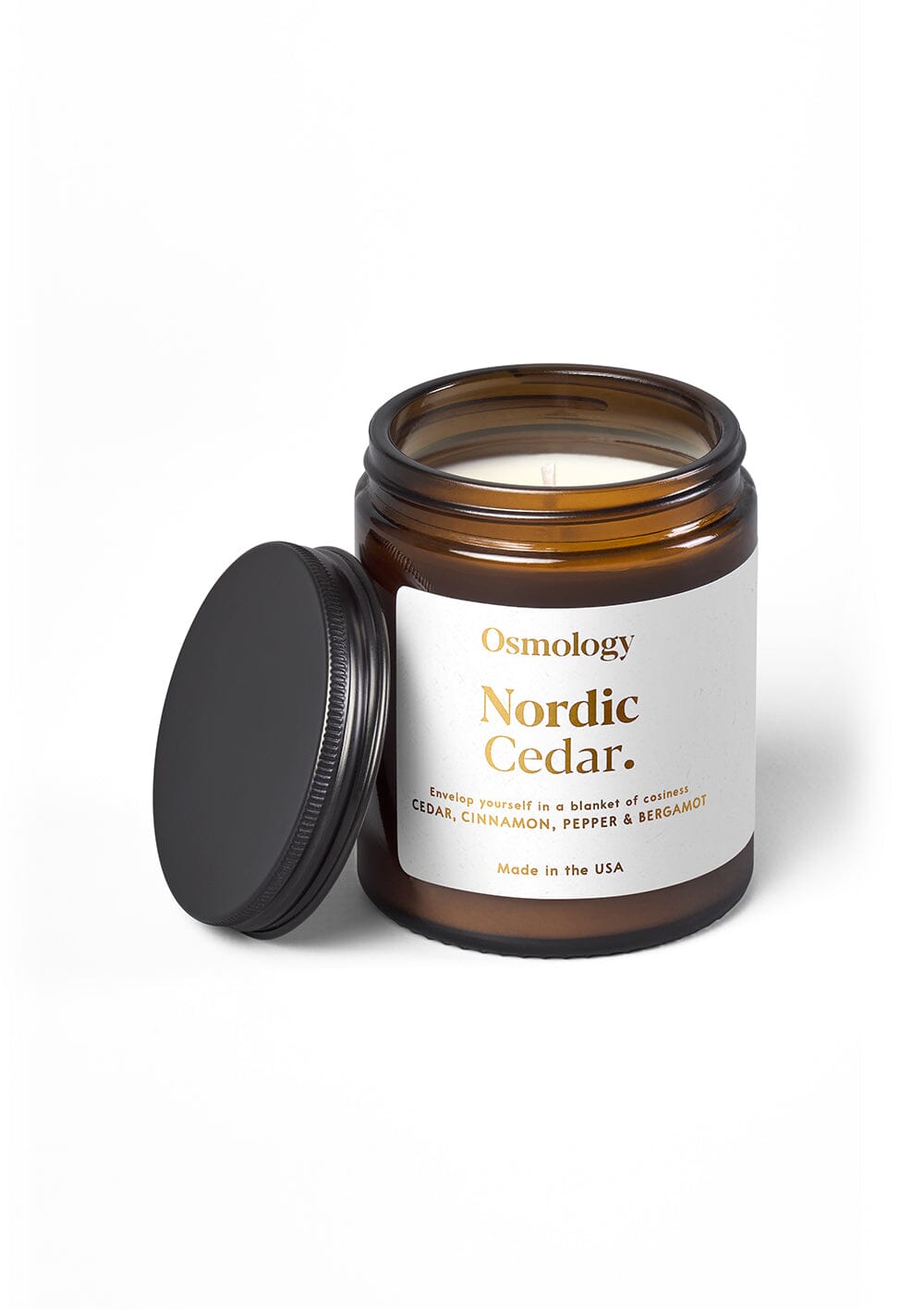 Osmology Nordic Cedar jar candle with open lid on cream background
