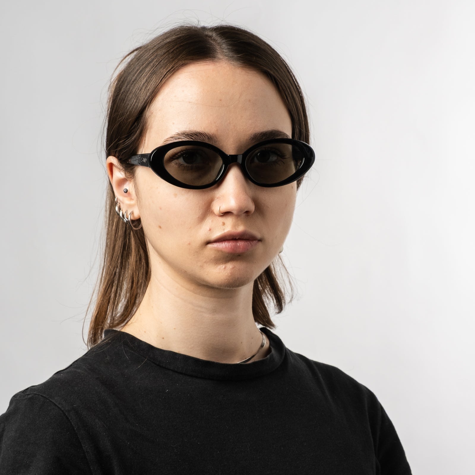 Female wearing Sad Eyewear Bloom oval sunglasses in black with tinted olive lenses