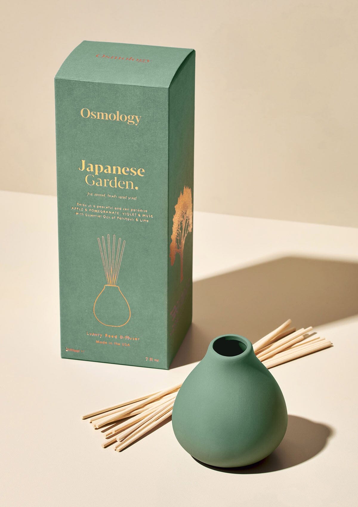 Osmology green ceramic reed diffuser next to product packaging on a white background