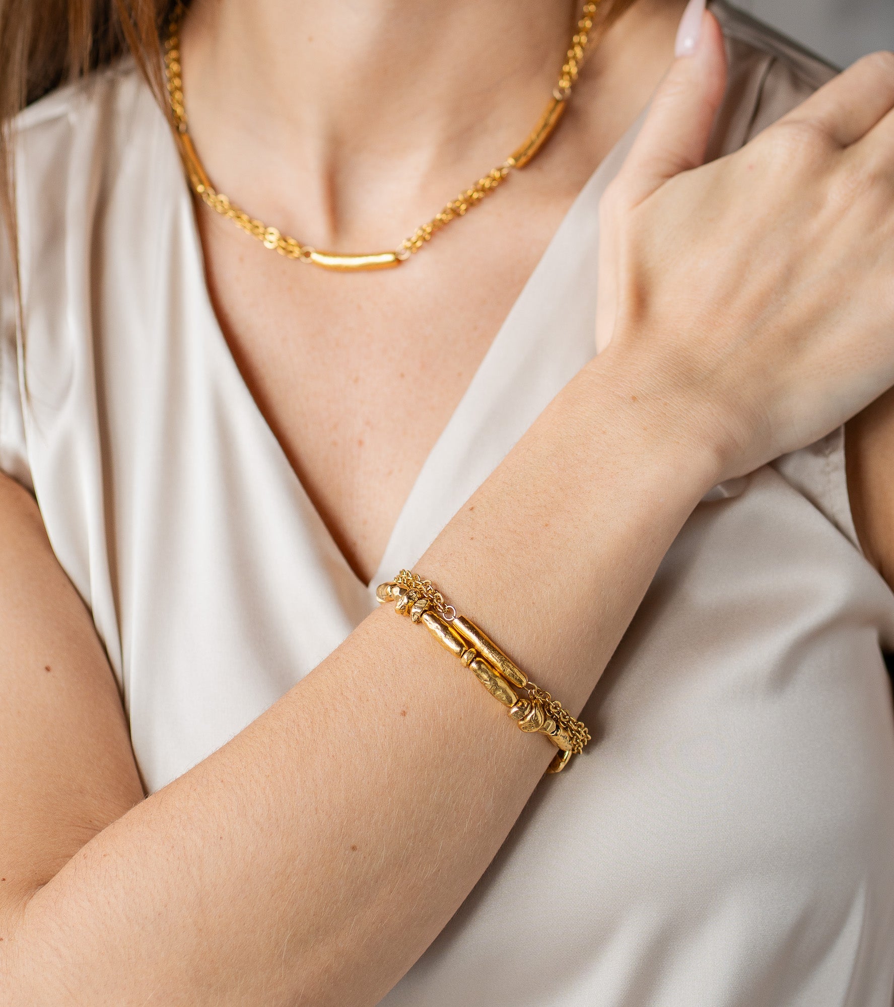 Gold bracelet with a single textured tube bead and double-strand chain.