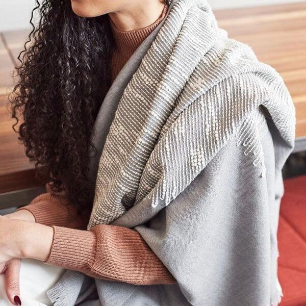 Flo Gray Textured Handloom Merino Throw elegantly draped over a person, showcasing its luxurious craftsmanship.