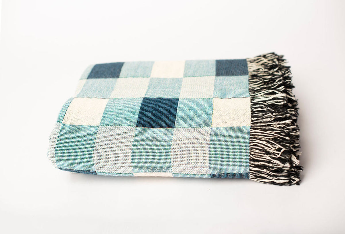 Close-up of Tilda Bayberry blue, aqua, and cream check woven cotton throw with fringe