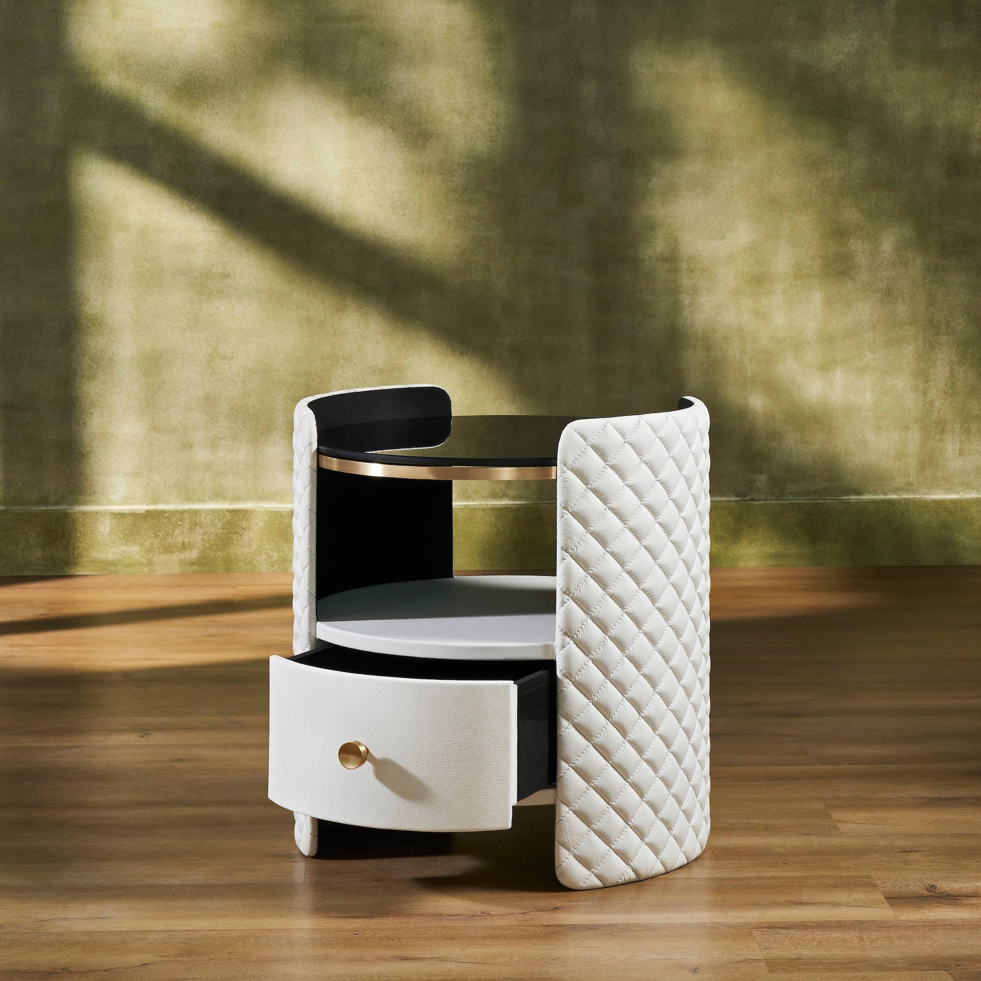 FN-5214-202022_3|White leather nightstand featuring diamond-quilted curved sides, a round black glass top, and one open drawer with a gold-toned knob.