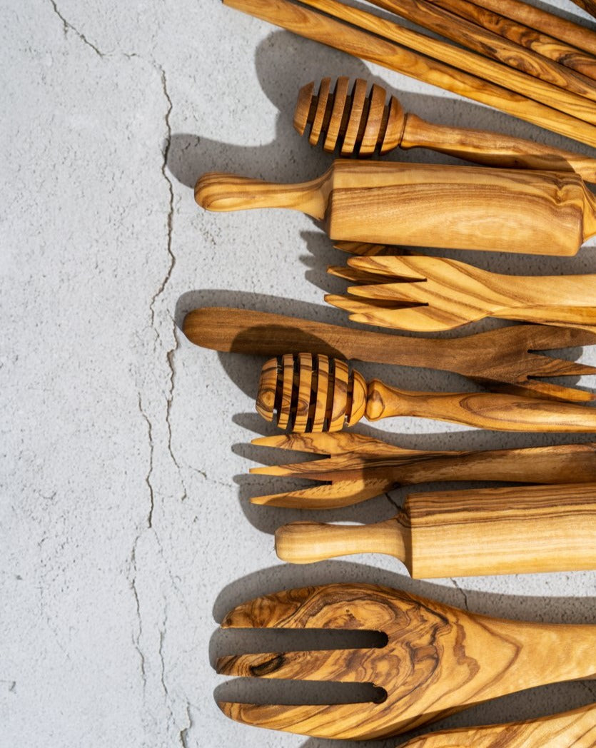 Assorted olive wood utensil sets, including honey spoons, displayed together.