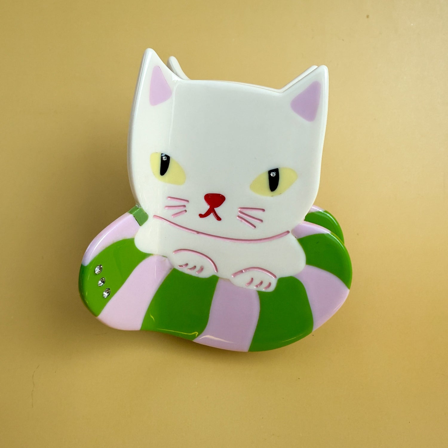This Kitty is an hedonist, he just vacations, he goes from Jeju Island to Oaxaca beaches to swim in his trendy and cool donut floaty. Have lots of fun this summer with our Vacation Kitty Hair Claw.