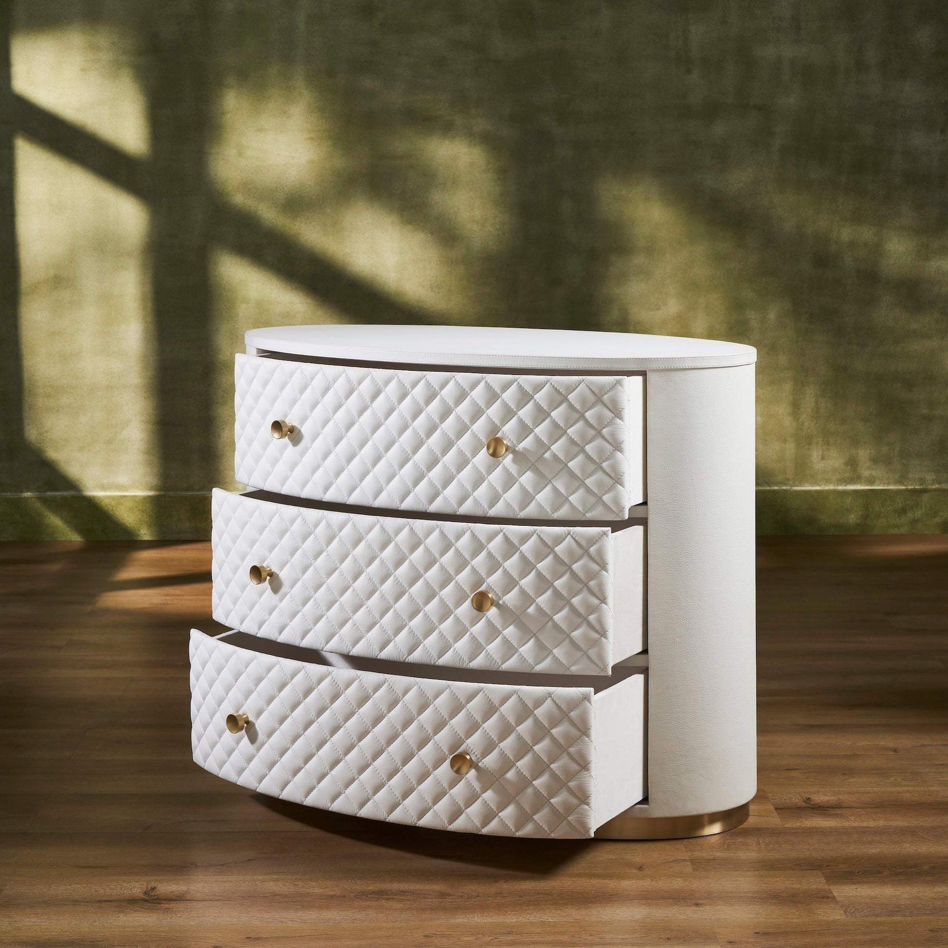FN-5218-482036_3|Elegant white leather oval chest of drawers, featuring a chic quilted design, radiant gold hardware, and a sleek gold base.