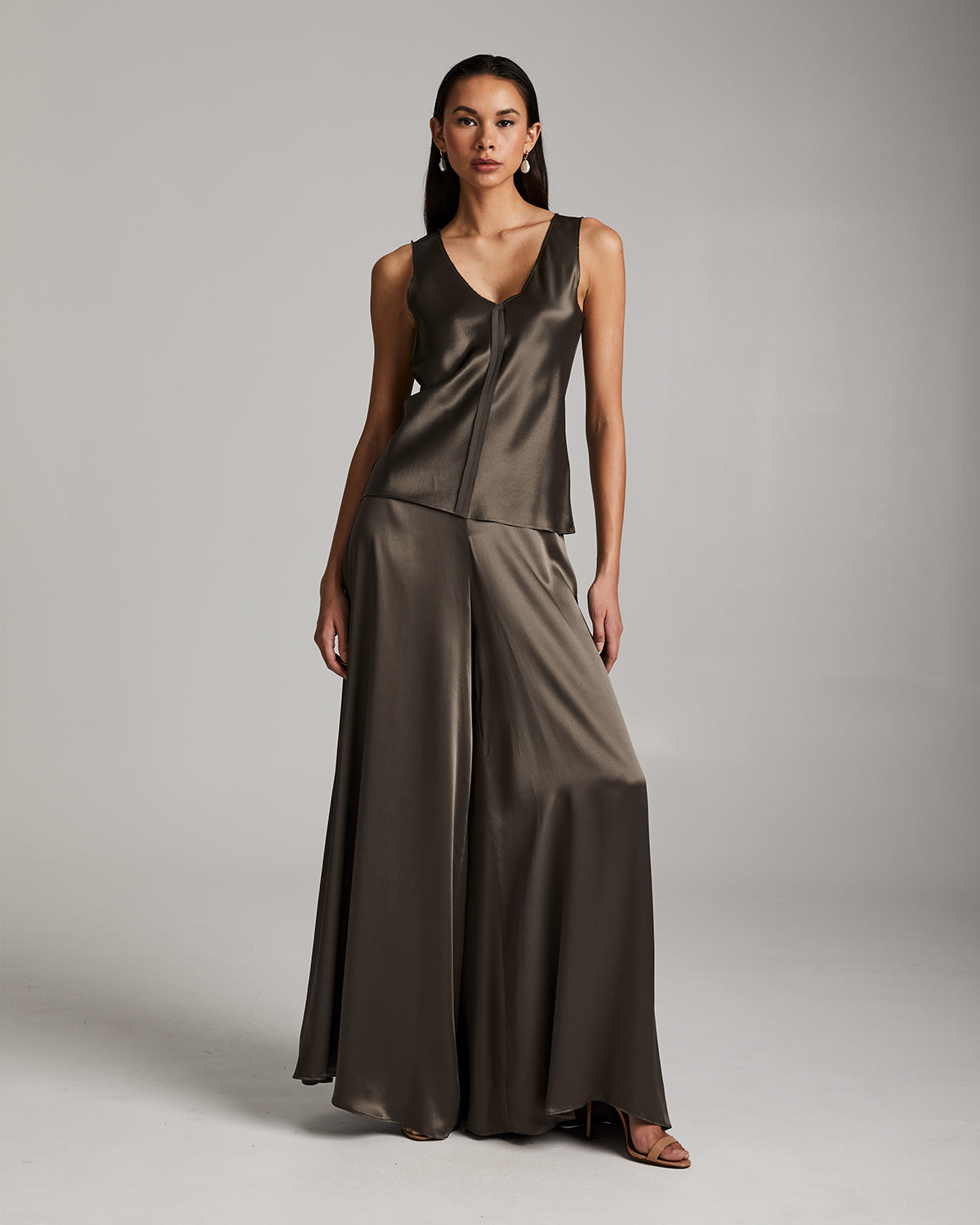Model wearing a silk raw edge tank top and palazzo pants in a neutral color.
