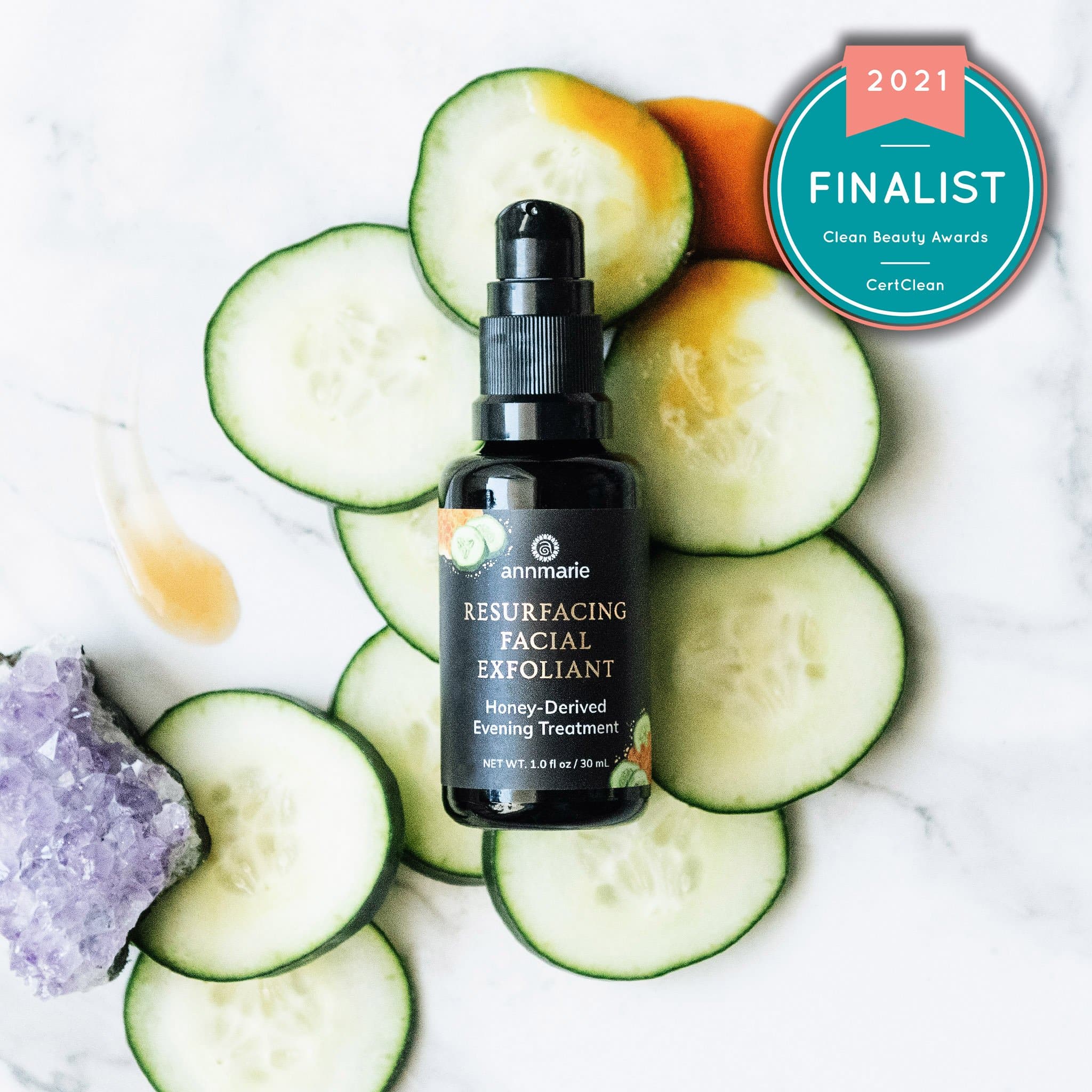 Bottle of 'annmarie' resurfacing facial exfoliant surrounded by cucumber slices on a white background with a 2021 finalist badge.
