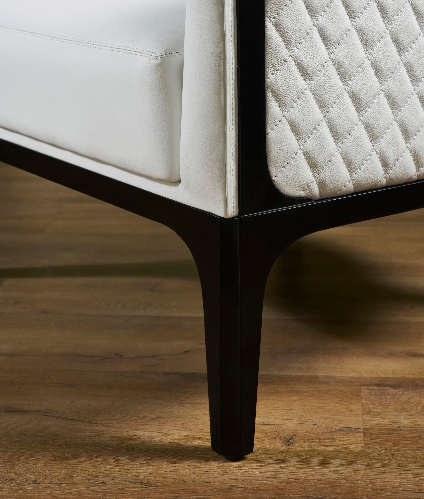 FN-5204-343329_7|Close-up of dark wood legs and base of a white leather armchair, emphasizing modern luxury leather furniture construction.