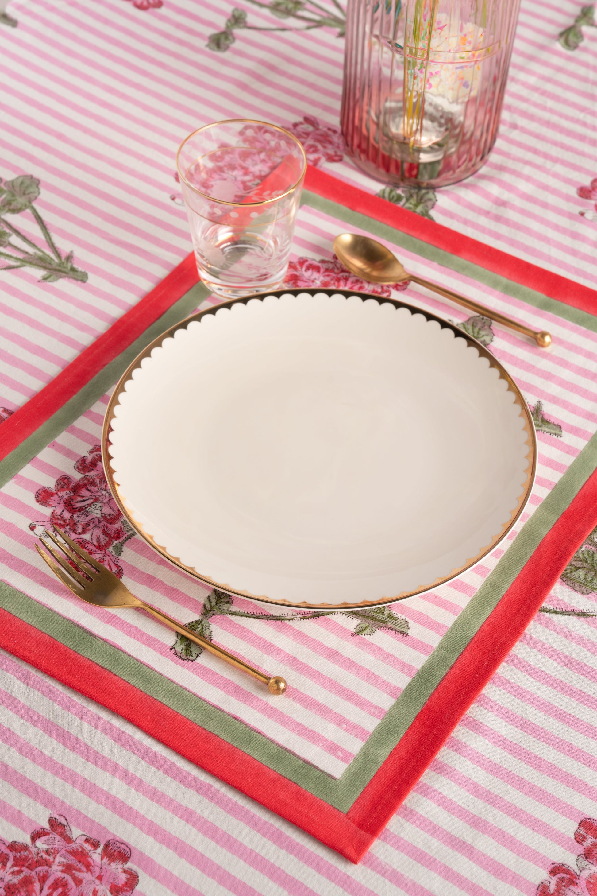 Pink hydrangea blockprint placemat with empty white plate and gold utensil