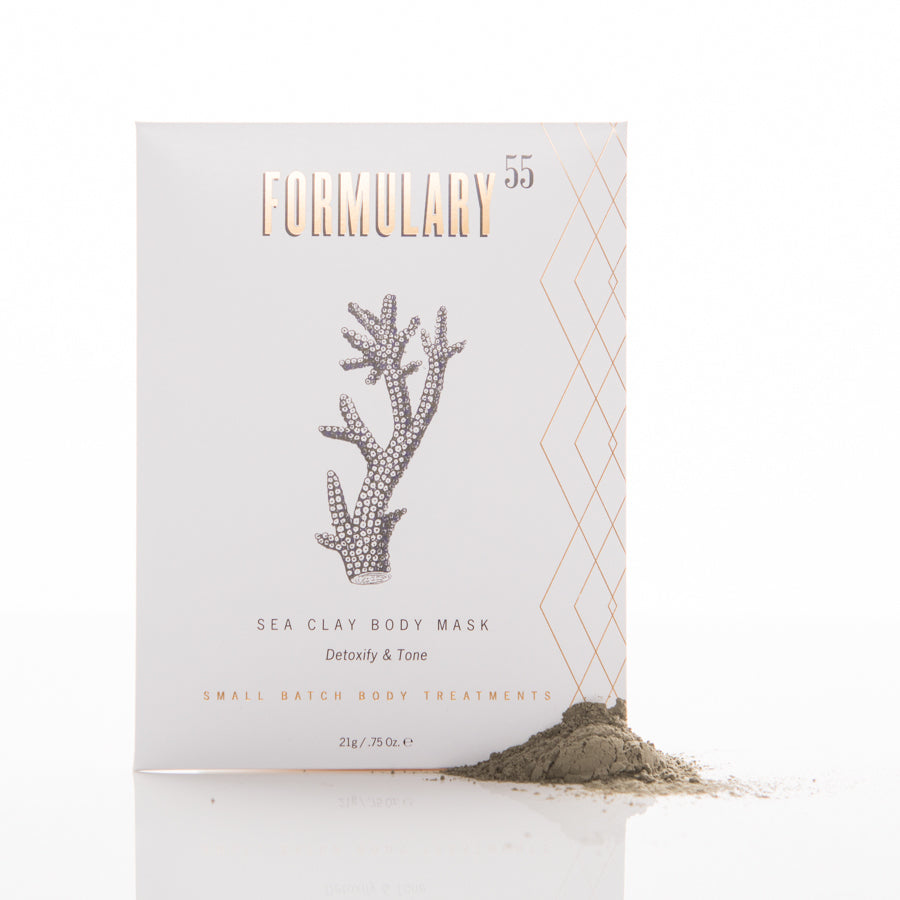 The image shows a white box of Formulary 55 Sea Clay Body Mask, with gold and gray text. The front has an illustration of coral. At the box's base, a small mound of gray powdered mask is spilled out. Text indicates the mask is for detoxifying and toning.