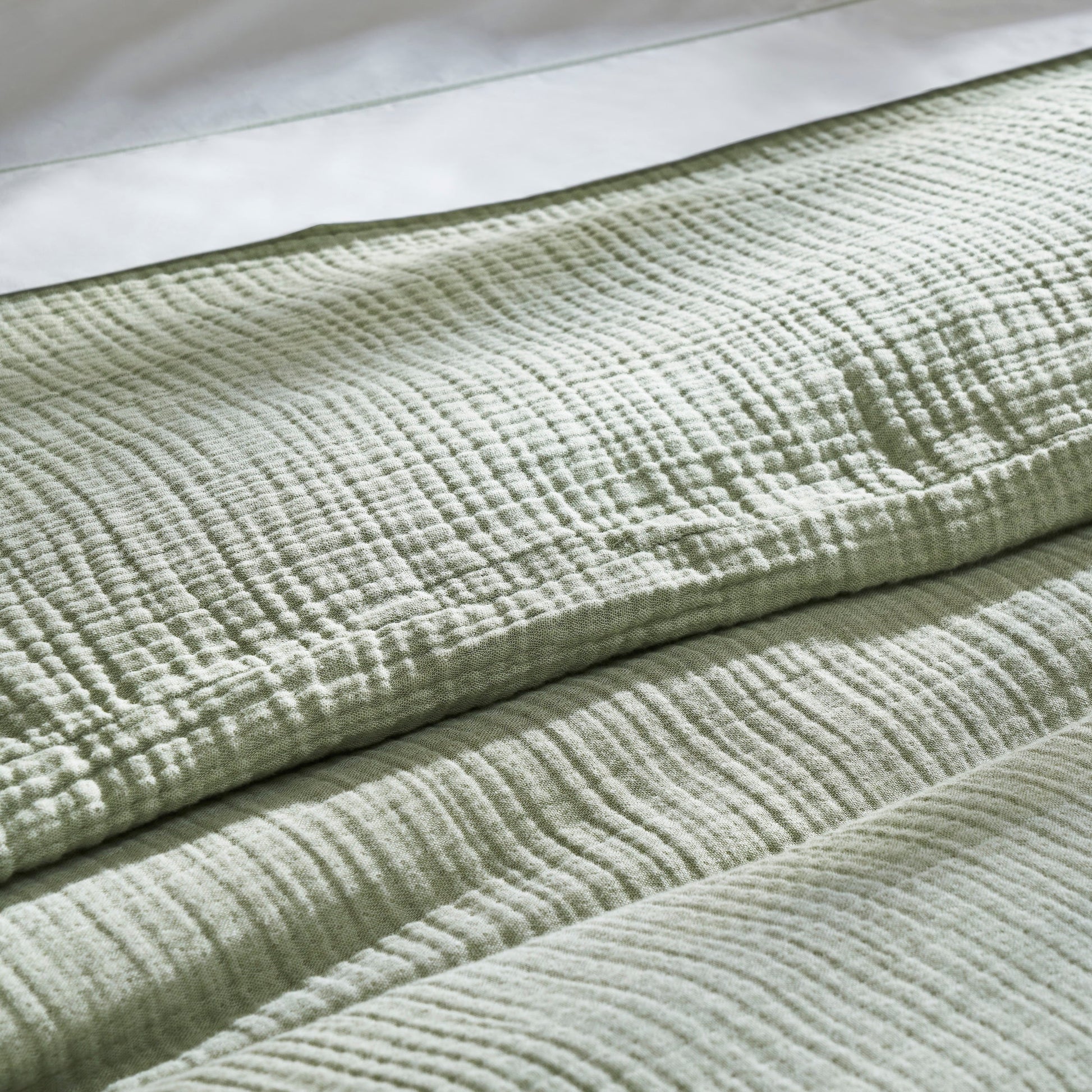 DT-051-9092_7|Detailed close-up of the crinkled texture of a sage green cotton duvet cover, emphasizing its soft, inviting feel.