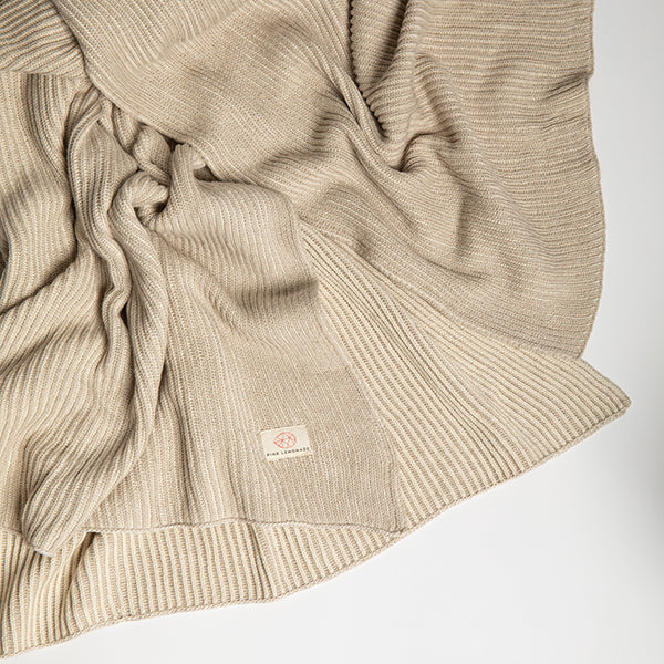 Natural and beige knitted cotton throw blanket with a Pink Lemonade brand label on a light gray background.