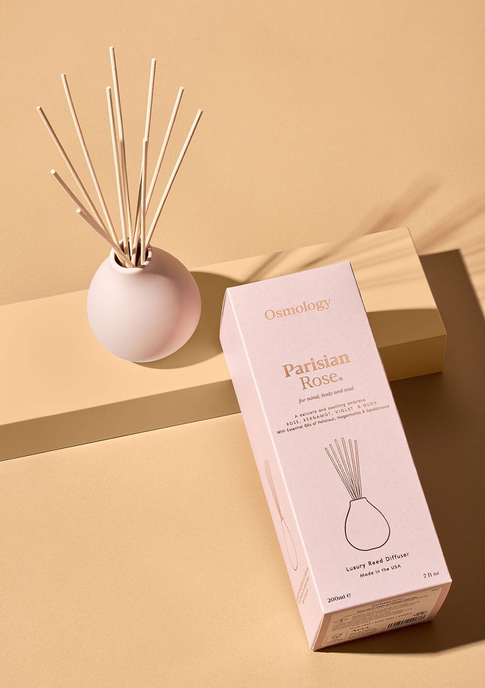 Osmology pale pink reed diffuser next to product packaging on a white background