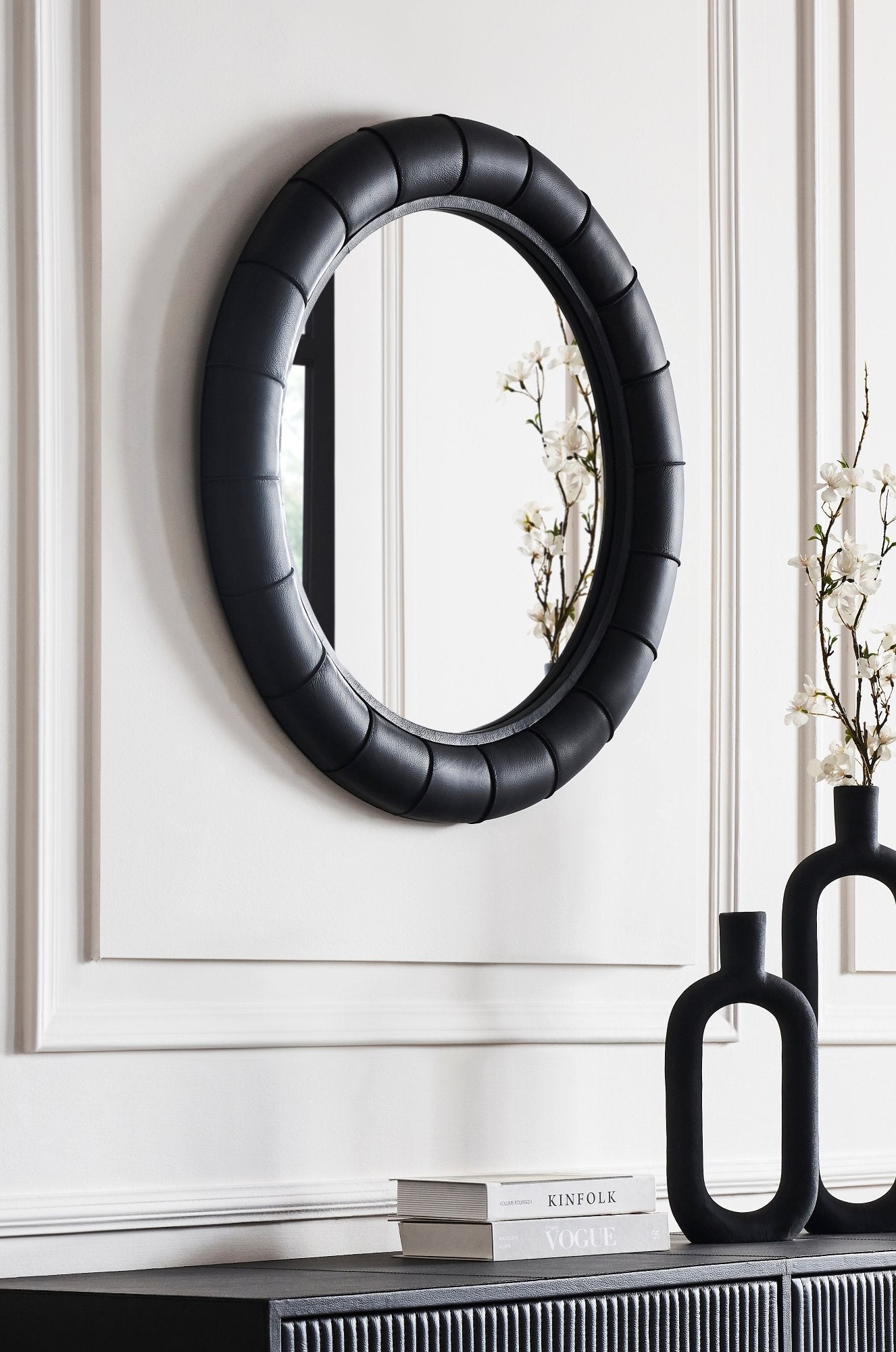 FN-5202-33233_2|Stylish black leather-framed round mirror, featuring a padded, channel-tufted frame, enhancing contemporary leather furniture decor.