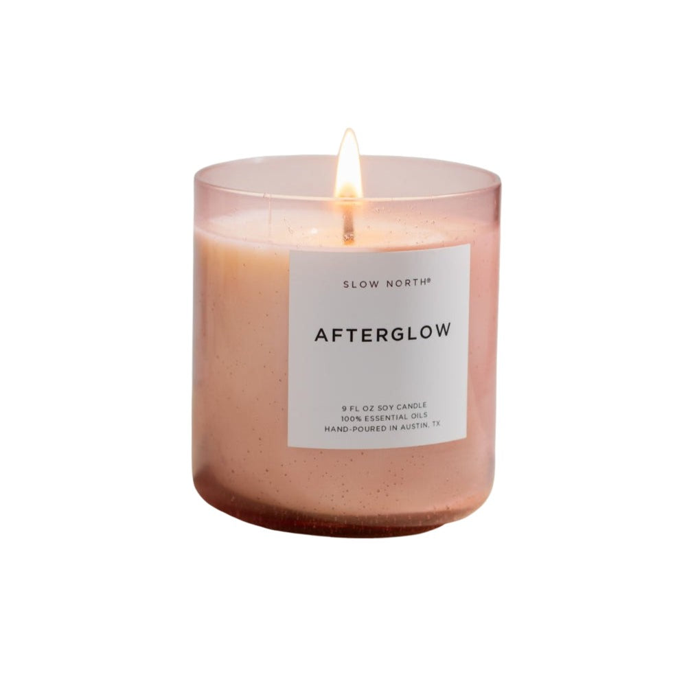 Pink candle labeled 'Afterglow' on a light stone surface with a neutral background