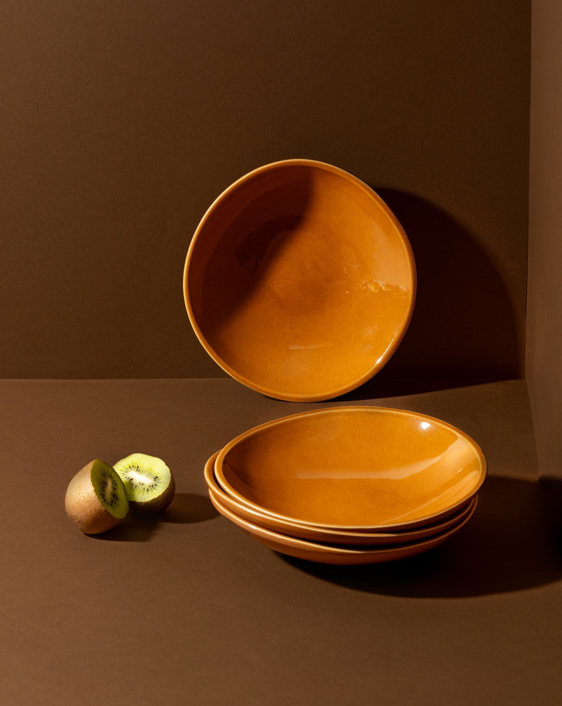 Two stoneware dessert plates with a matte finish, one containing some food residue, placed on a textured surface with a fork and spoon to the side.