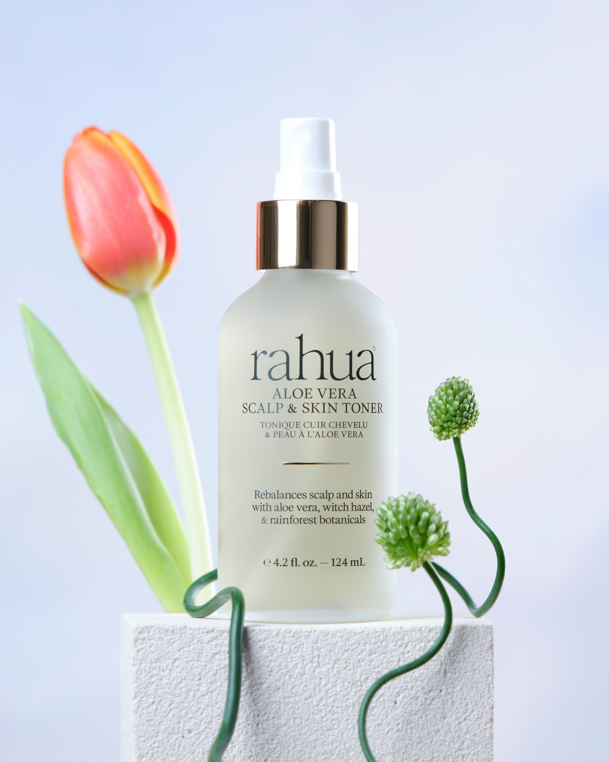 Bottle of rahua aloe vera scalp and skin toner with flowers on a light background|variant:42-oz