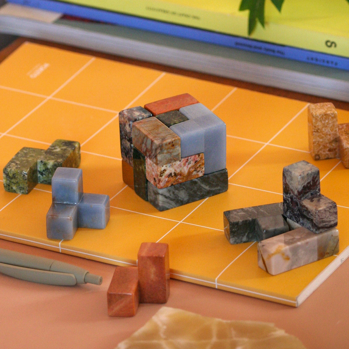 Disassembled gemstone Soma puzzle pieces resting organically in a quiet luxury setting.