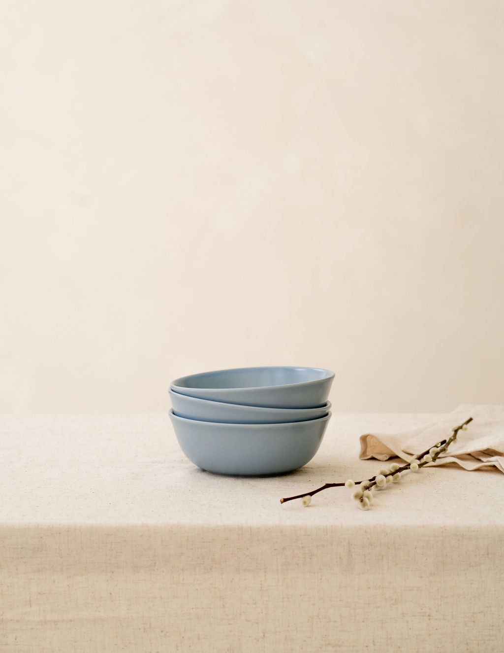 Stack of Wave blue non-toxic ceramic bowls from Hamkke Home on a neutral tablecloth for product display.