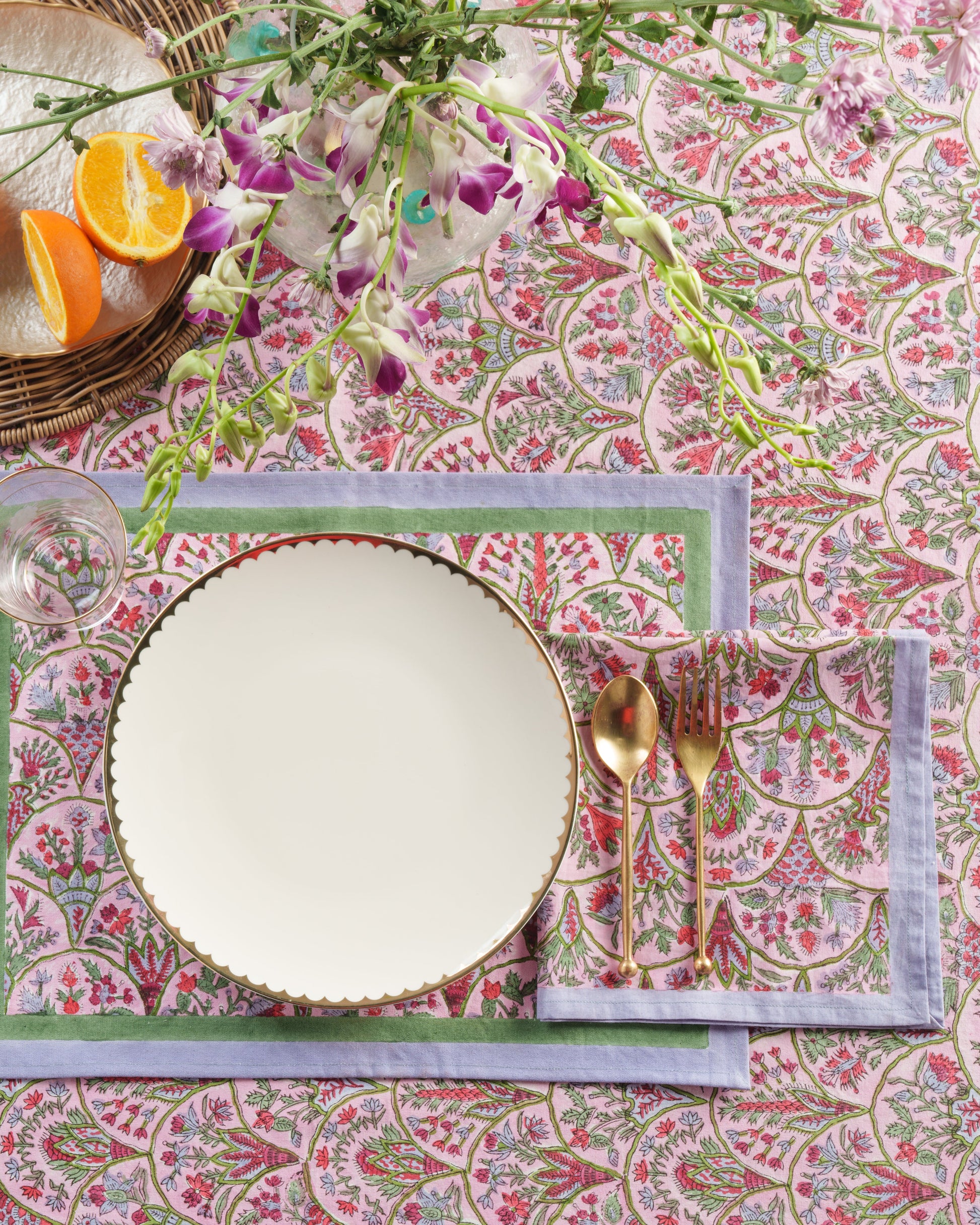 Pink arch blockprint placemat with gold utensils and empty plate