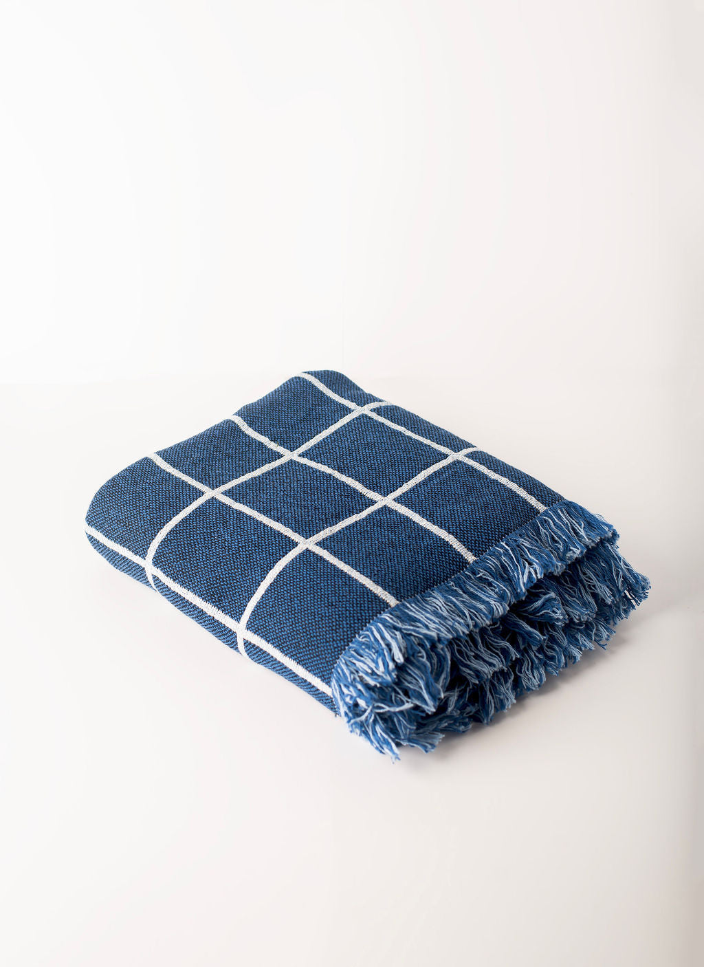 Close-up of Greer Lapis blue and cream windowpane grid woven cotton throw with fringe