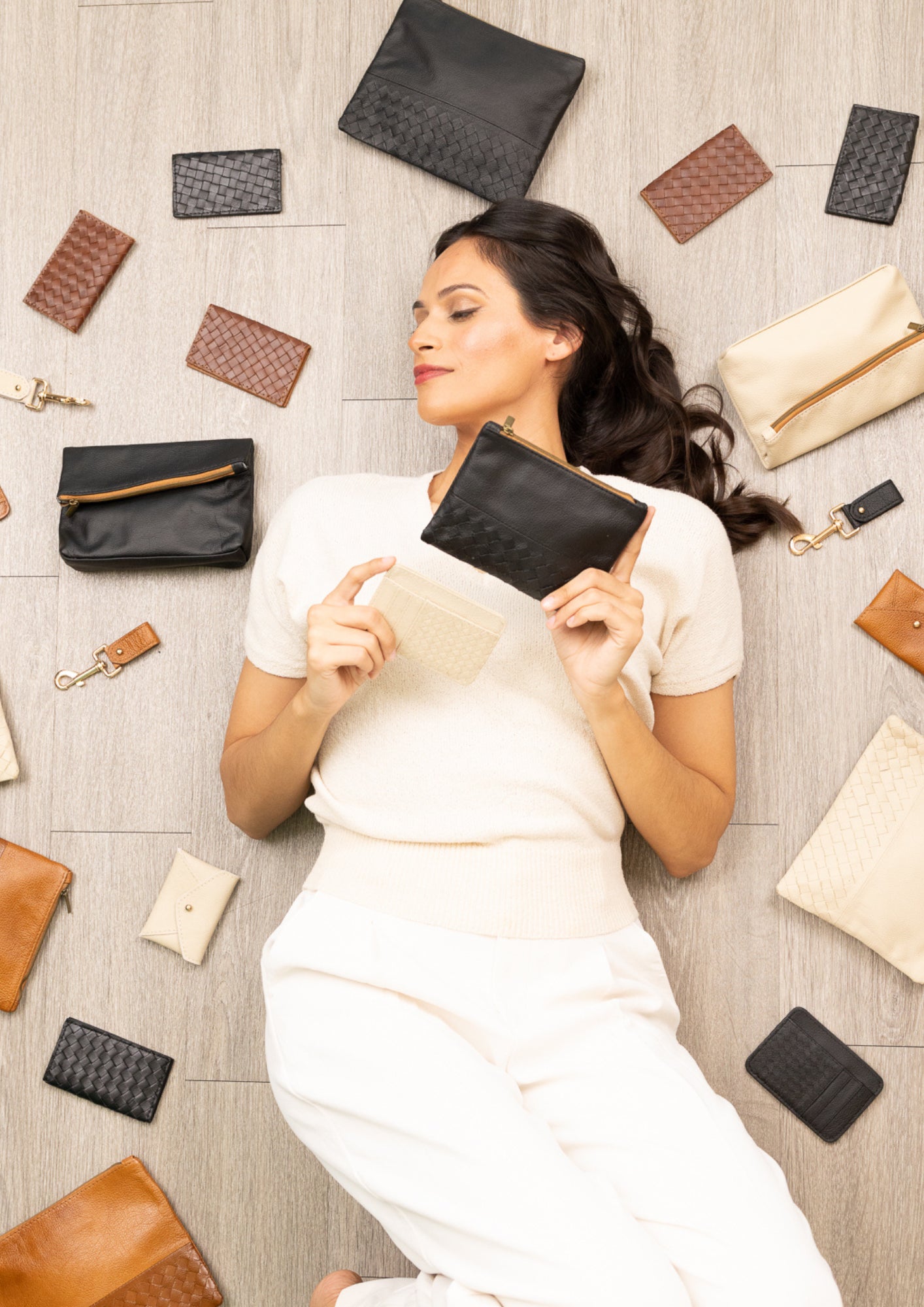 model lying down surrounded by leather accessories.