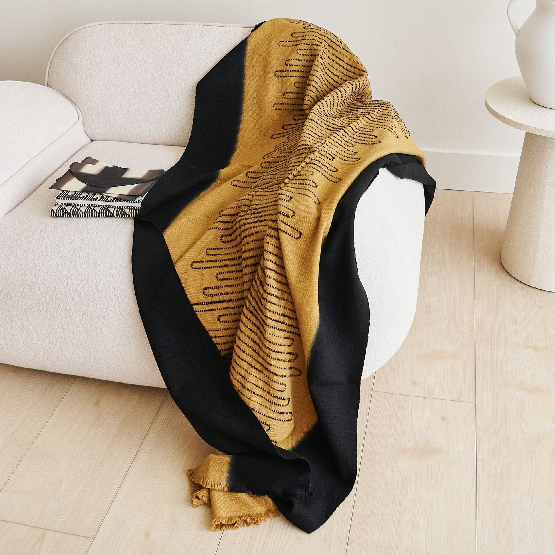 Handwoven Topaz Brown Myrtle Drift Merino Throw draped over a couch, showcasing its unique pattern and color contrast.