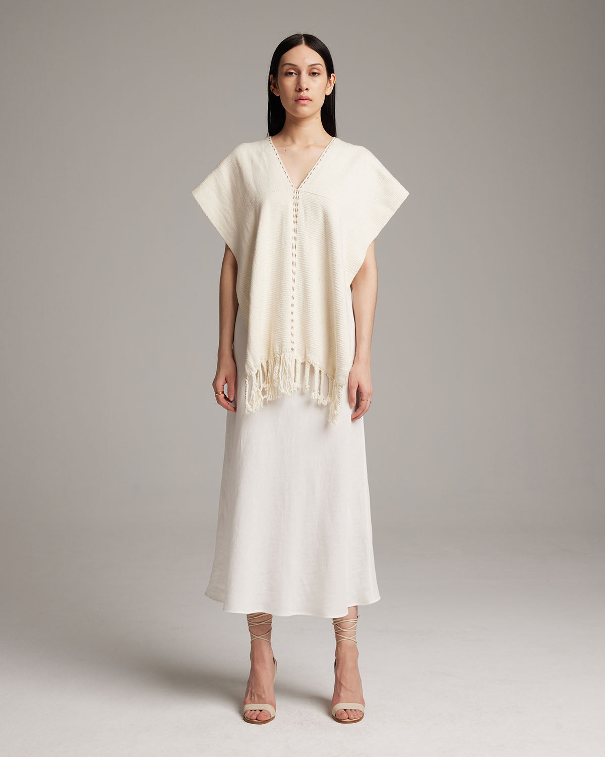 Model wearing a hand-loomed ivory Copper Threads Manta with fringe detail