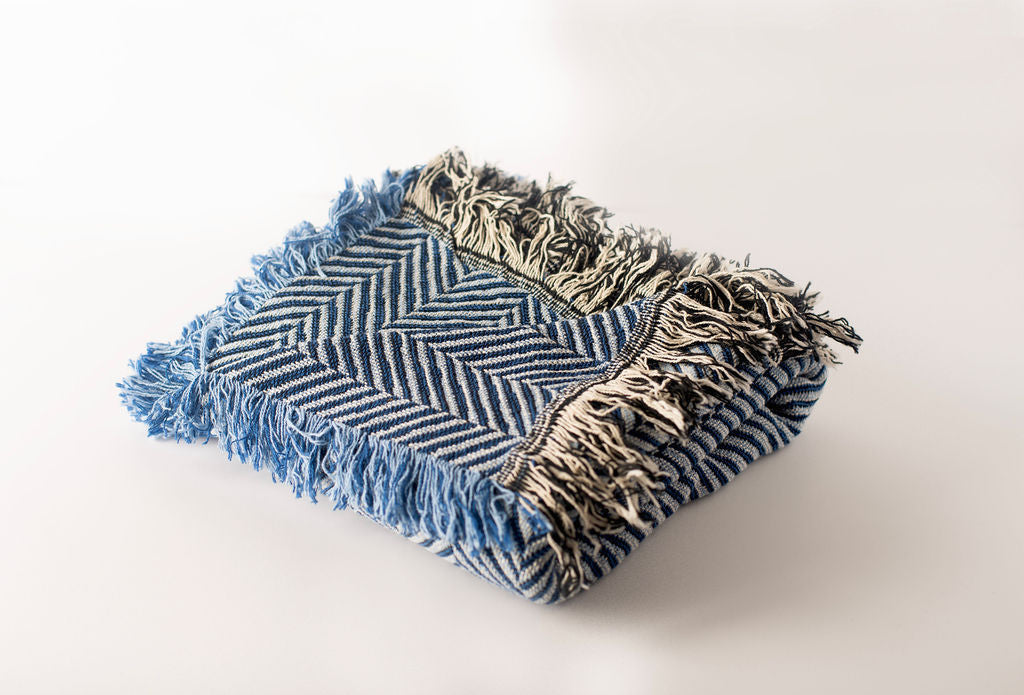 Henry Chambray blue herringbone throw folded to show its reversible woven construction and contrasting fringe