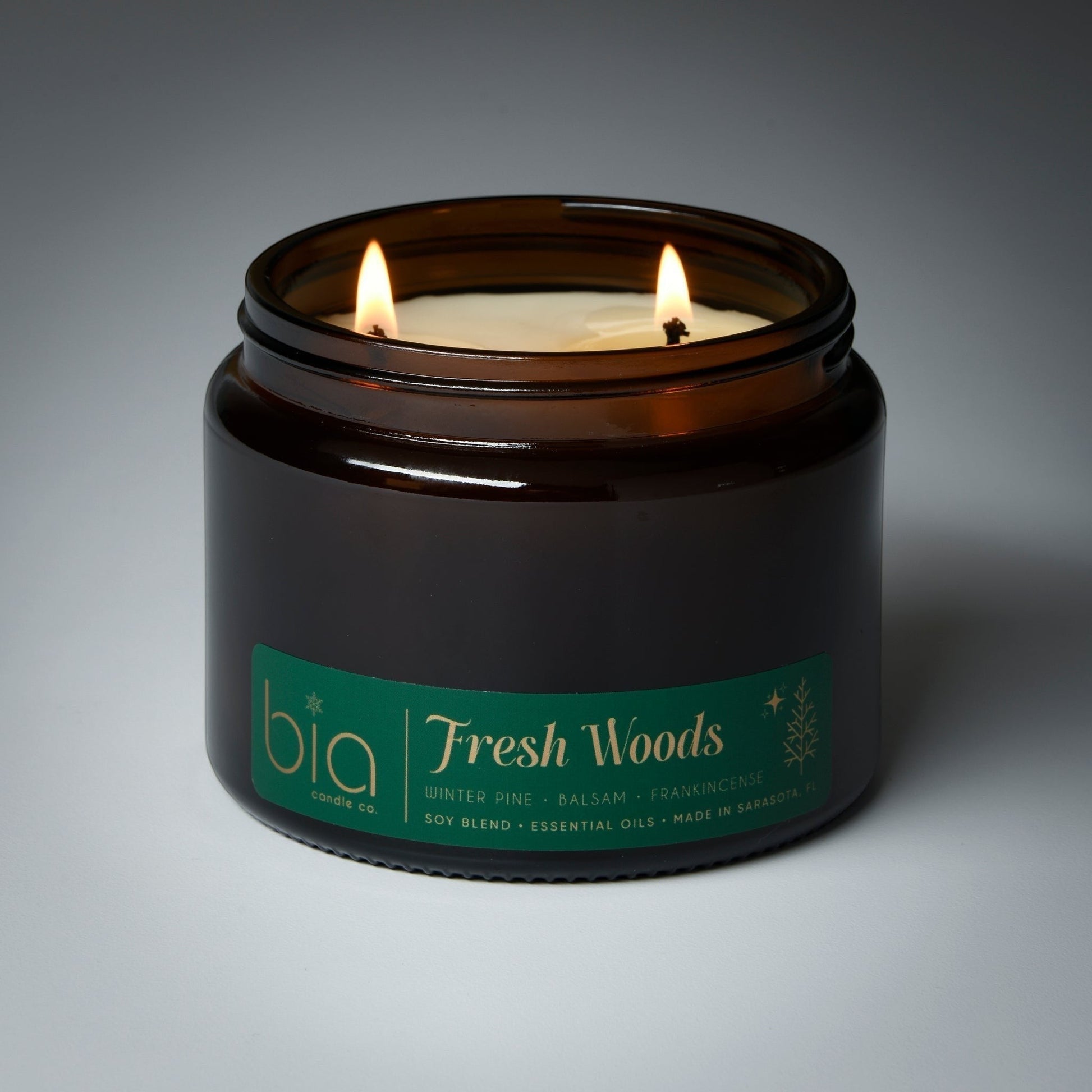 grande 2wick Candle in a brown jar labeled 'Fresh Woods' by bia on a gray background