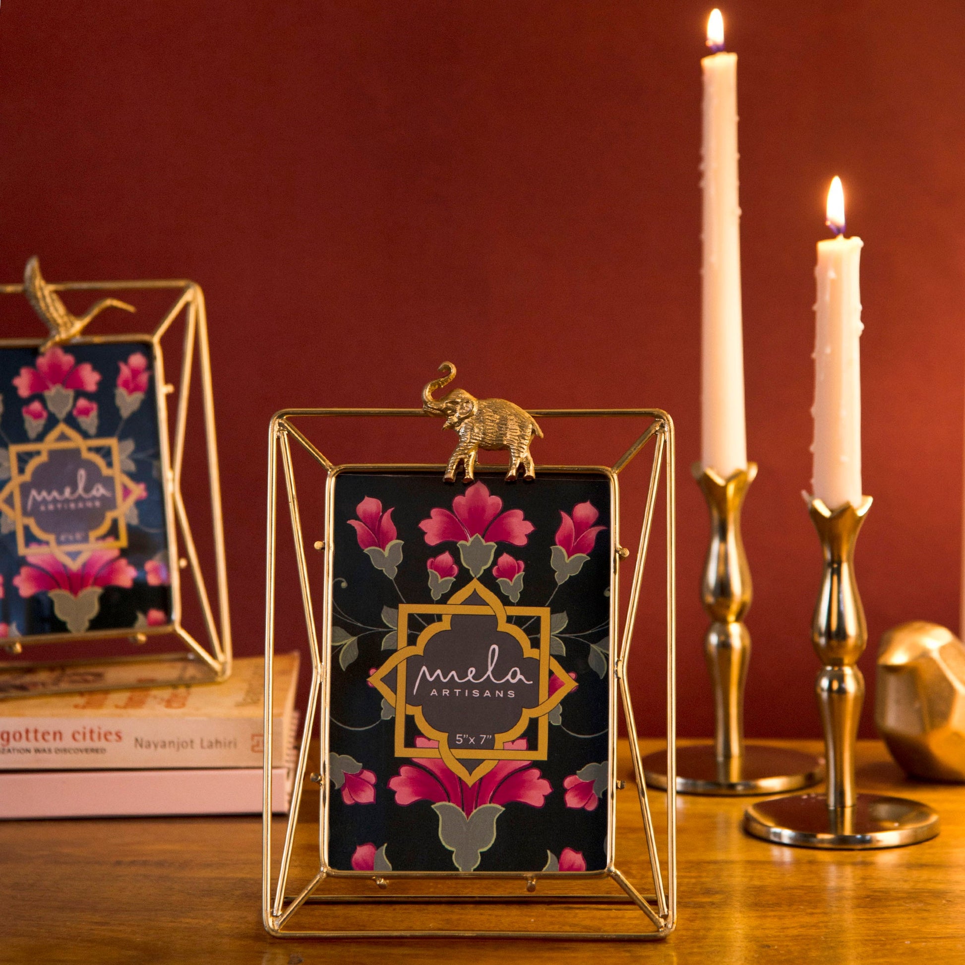 Elegant gold-finished metal picture frame with an artisanal elephant motif and geometric wire backing.