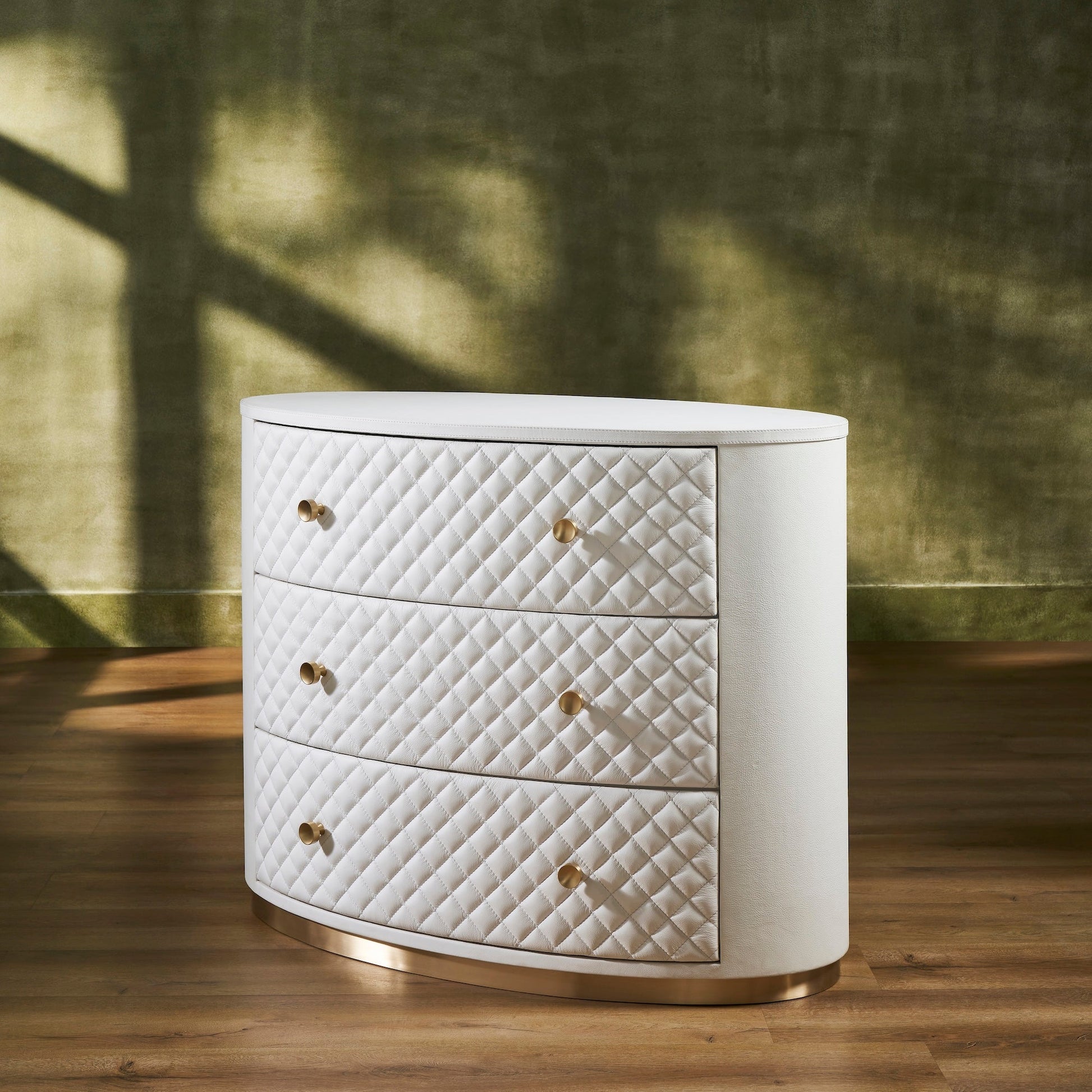 FN-5218-482036_2|Elegant white leather oval chest of drawers, featuring a chic quilted design, radiant gold hardware, and a sleek gold base.