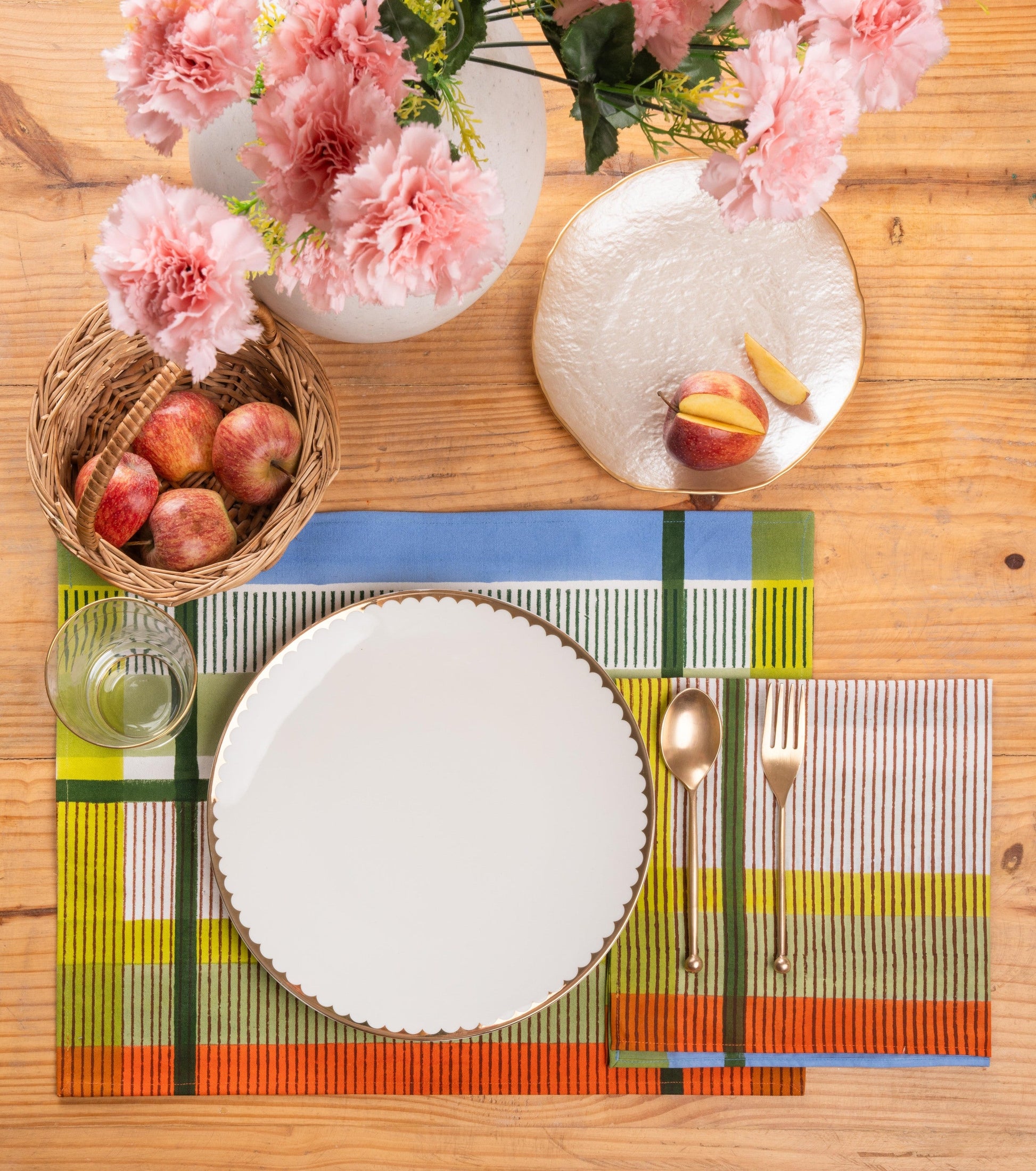 Modernist striped napkin set displayed on wooden table with plates and flowers