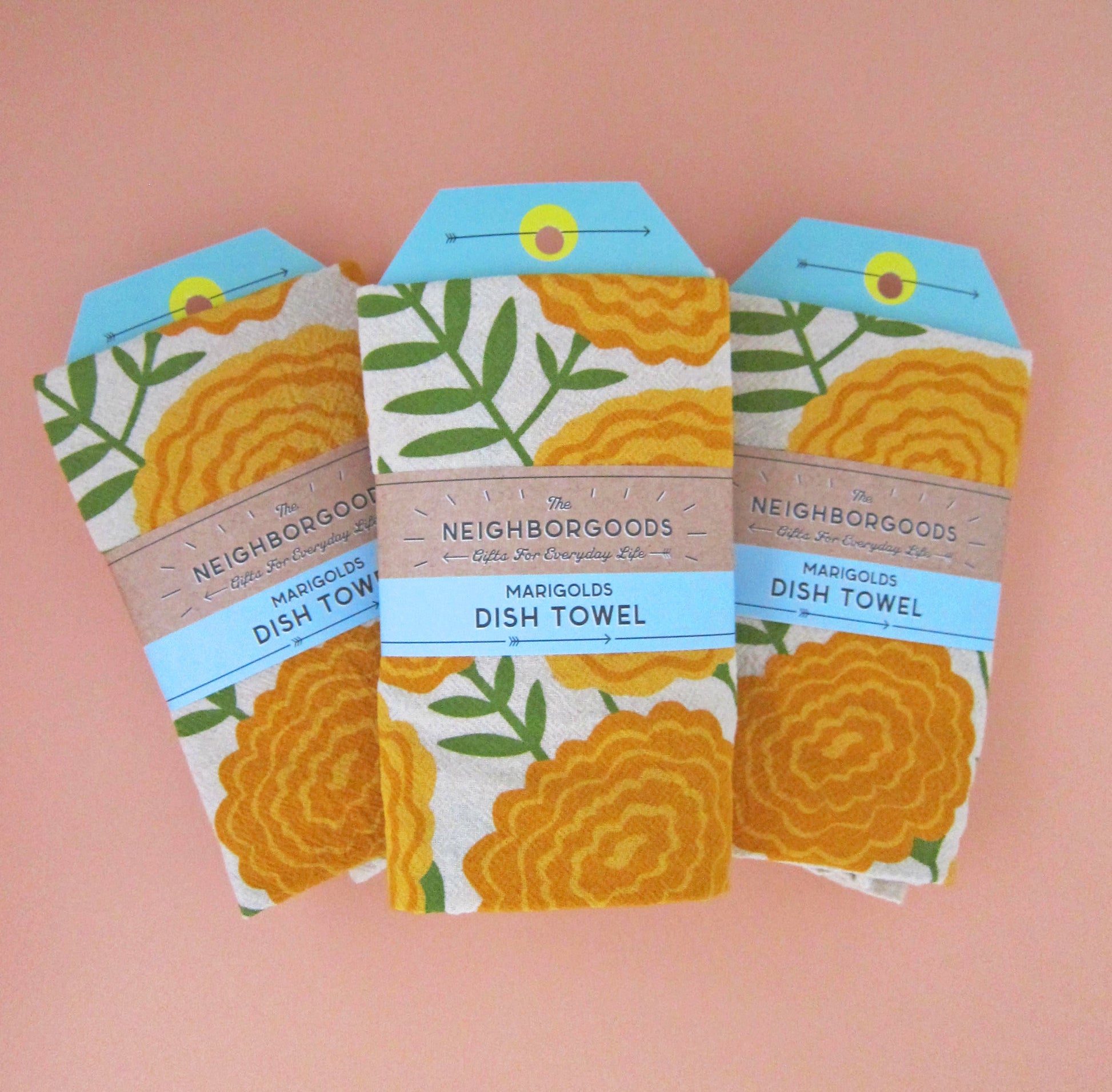 Front view of The Neighborgoods Marigolds dish towel in a ready-to-gift sleeve.