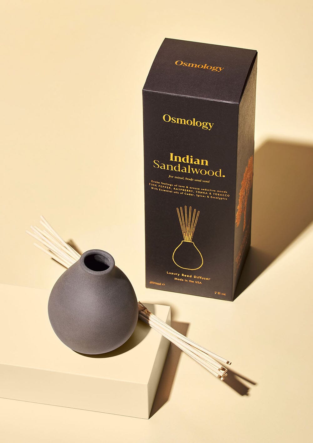 Osmology black ceramic Indian Sandalwood reed diffuser next to product packaging on a white background