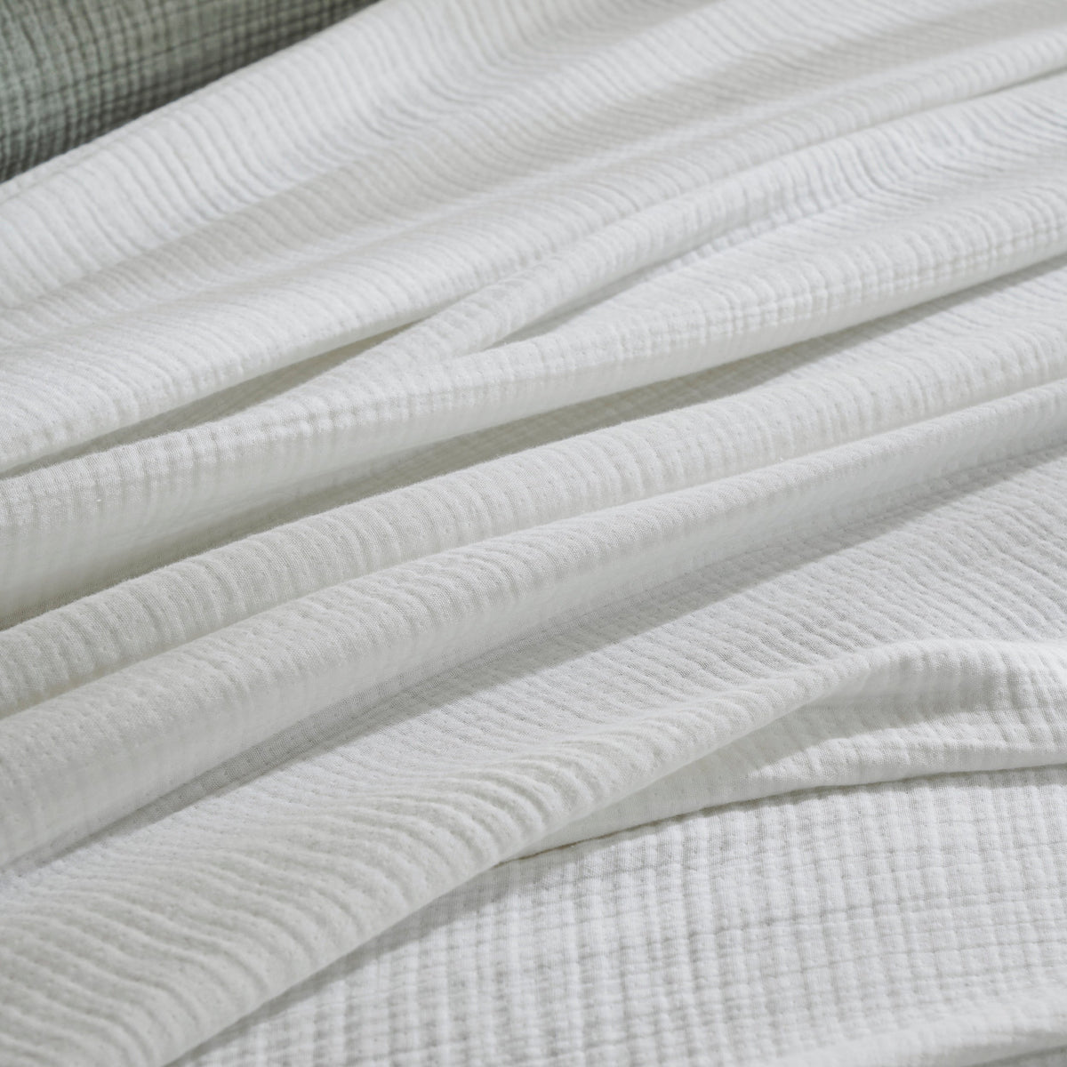BL-861-9496_5|Close-up of a soft white textured crinkled blanket, showcasing its breathable gauzy cotton fabric and cozy, inviting appearance.