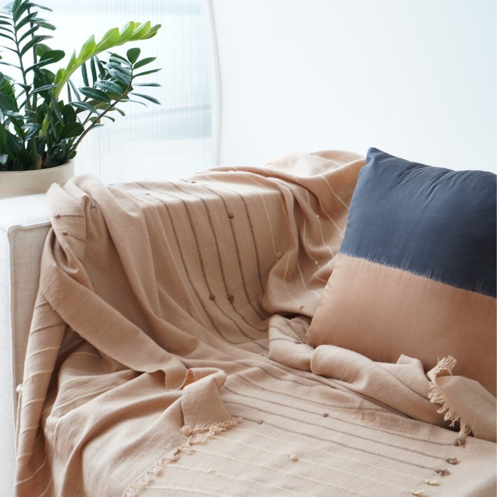 Kala Black & Gold Color Block Mulberry Silk Square Pillow on a cozy couch with a beige throw.